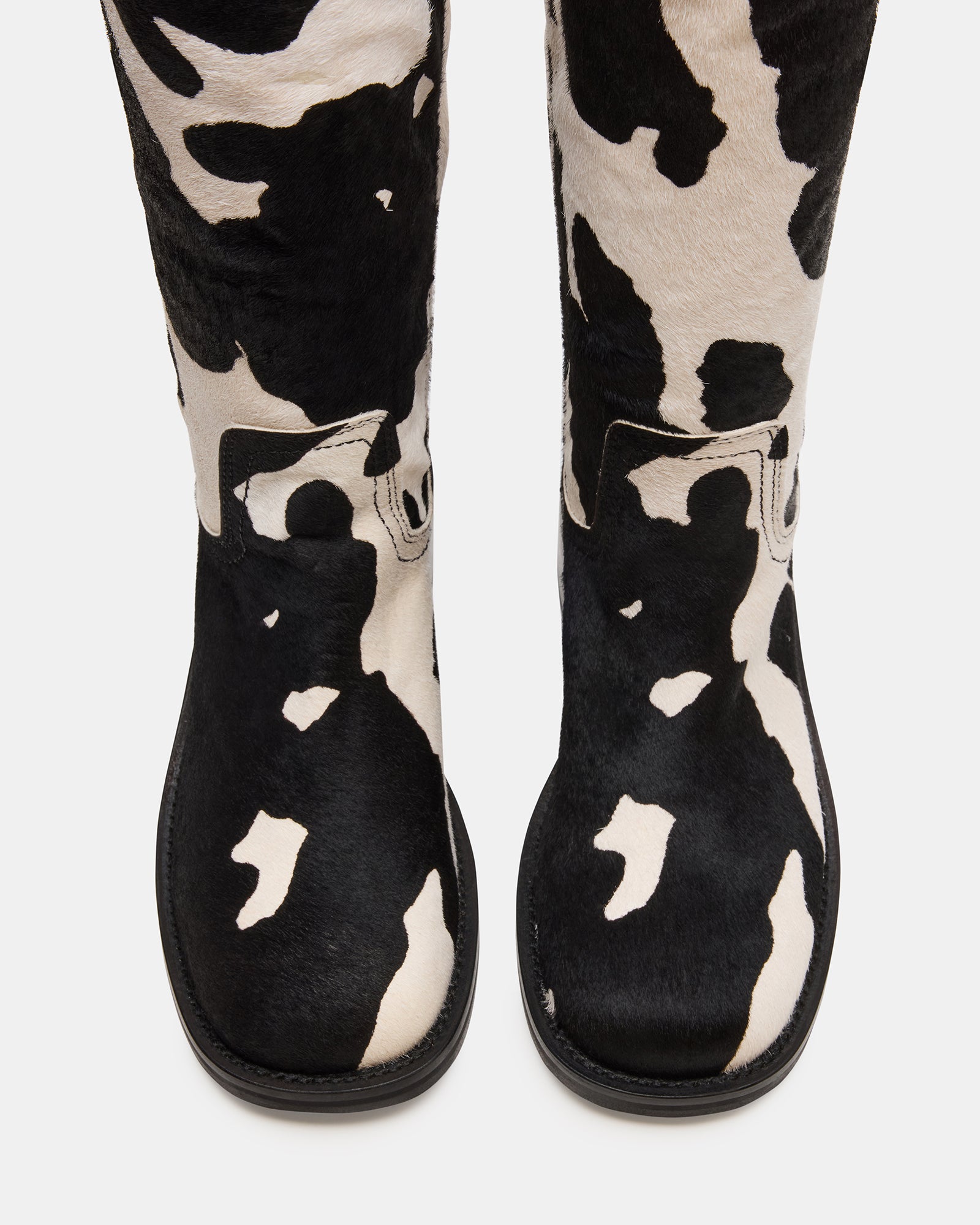 Side view of Riggs black cow print wide calf boots on a model