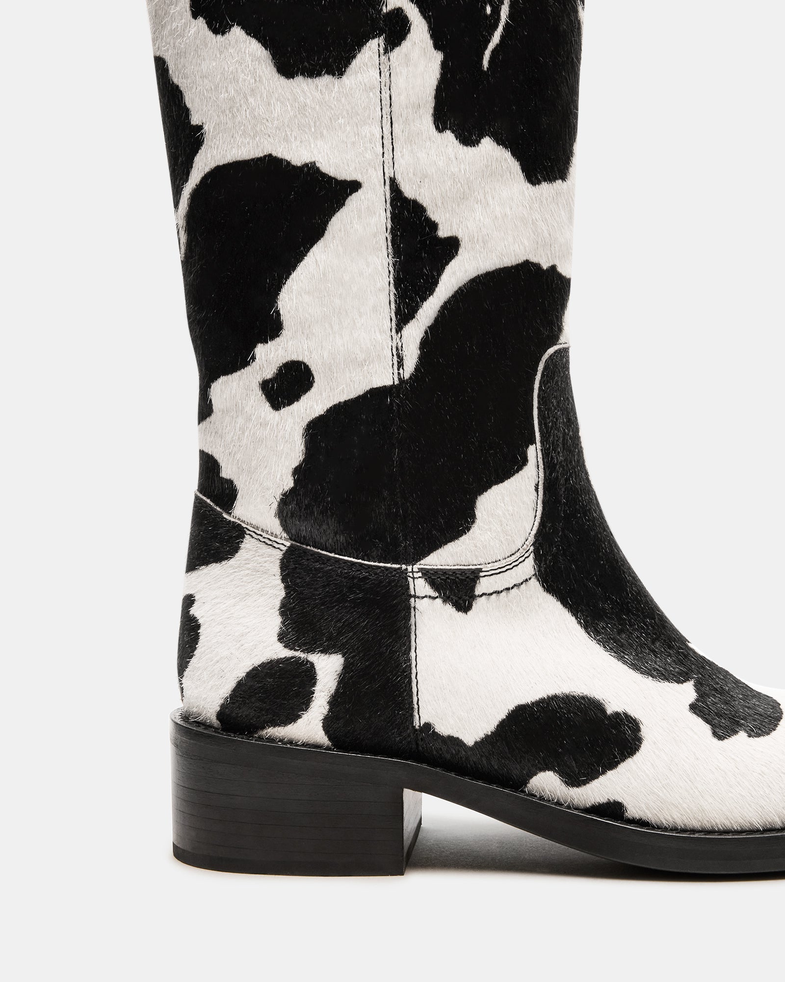 Close-up of the black cow print knee-high boots featuring a square toe.