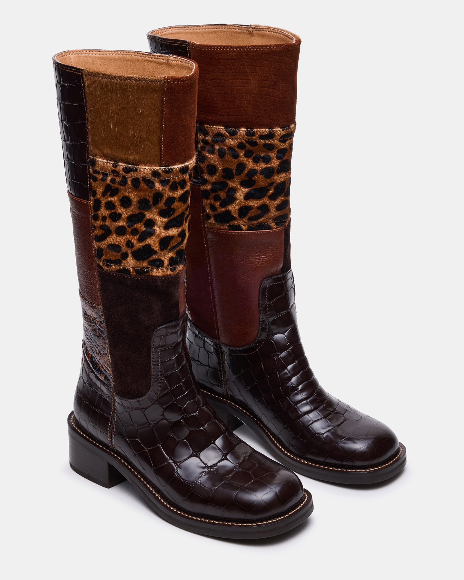 Model wearing brown leather boots with square toe while walking downtown