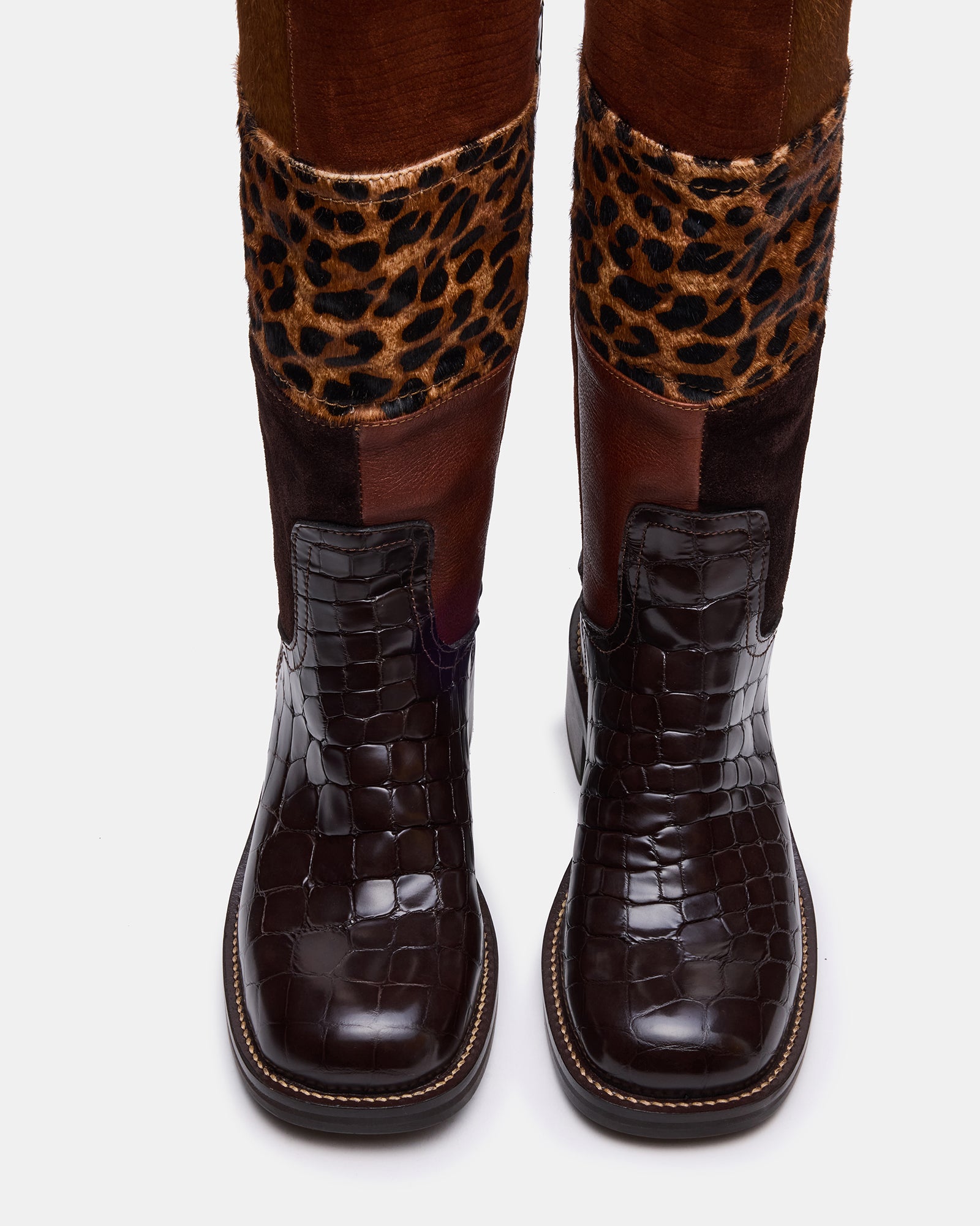 Side angle of fashion boots with suede and leather blend against city backdrop