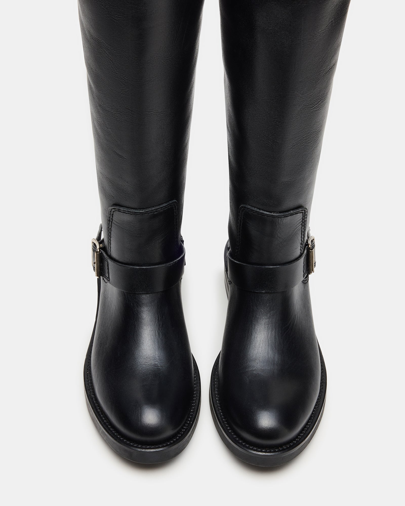 Side angle of knee-high black leather boots with buckled strap