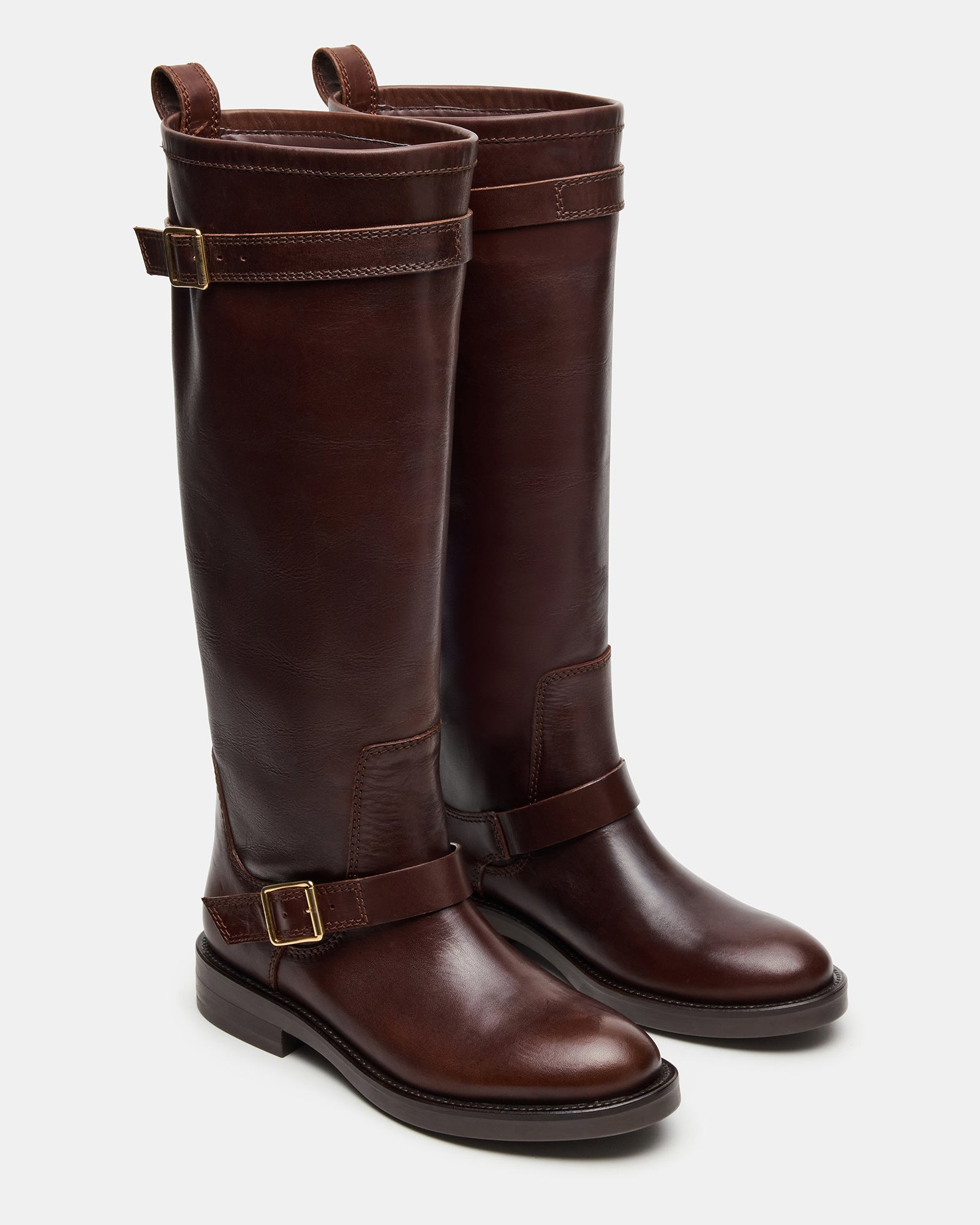 Close-up of the rounded toe and buckle detail on brown leather boots.