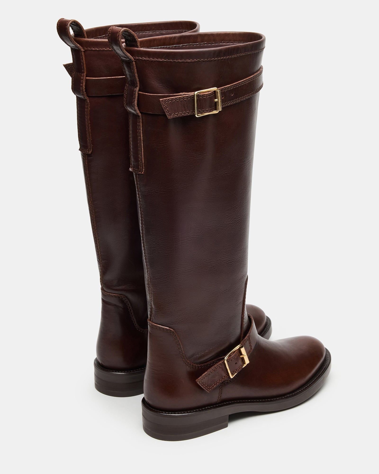 Close-up of the rounded toe and buckle detail on brown leather boots.