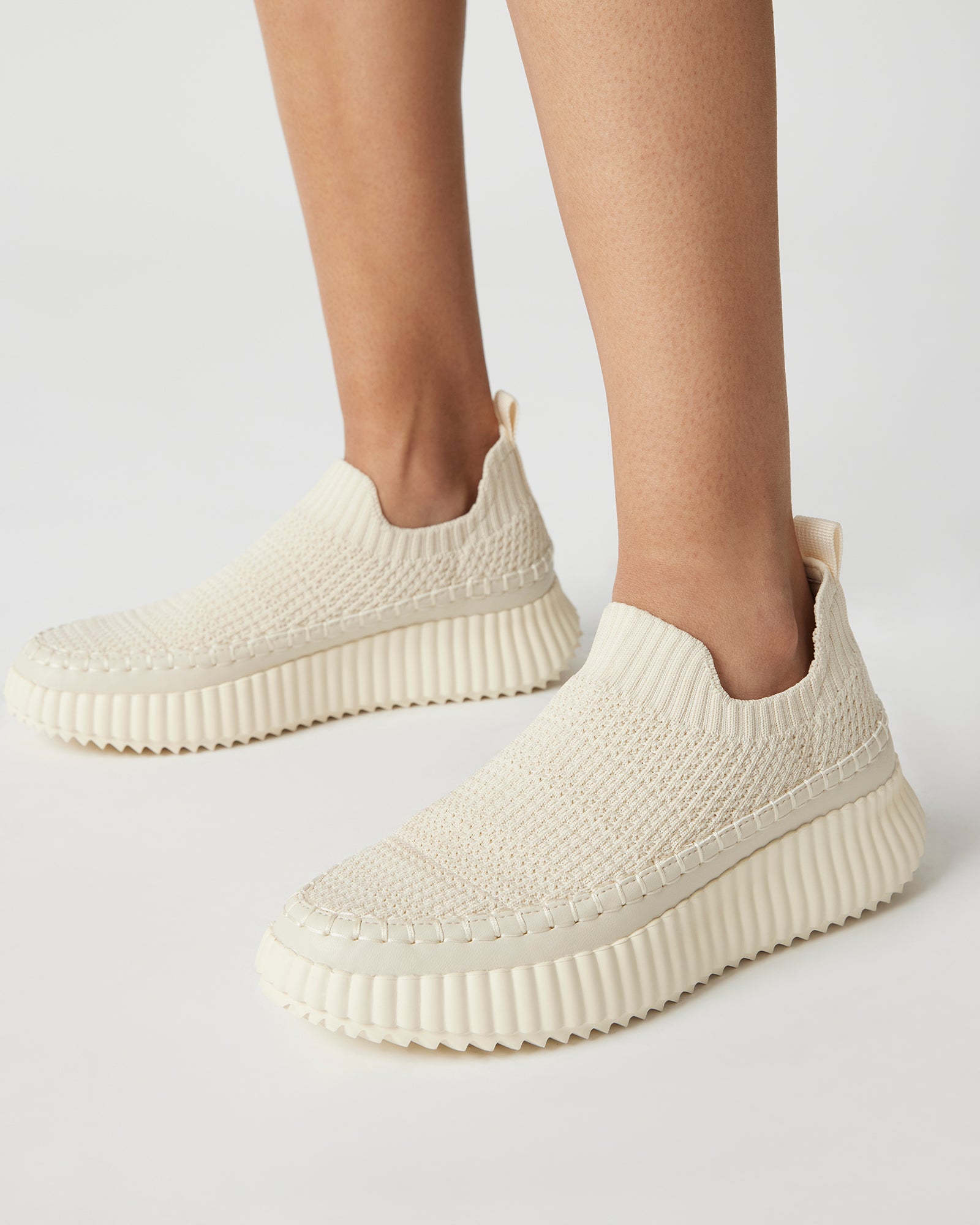 Close-up of the waffle weave texture on beige slip-on sneakers.