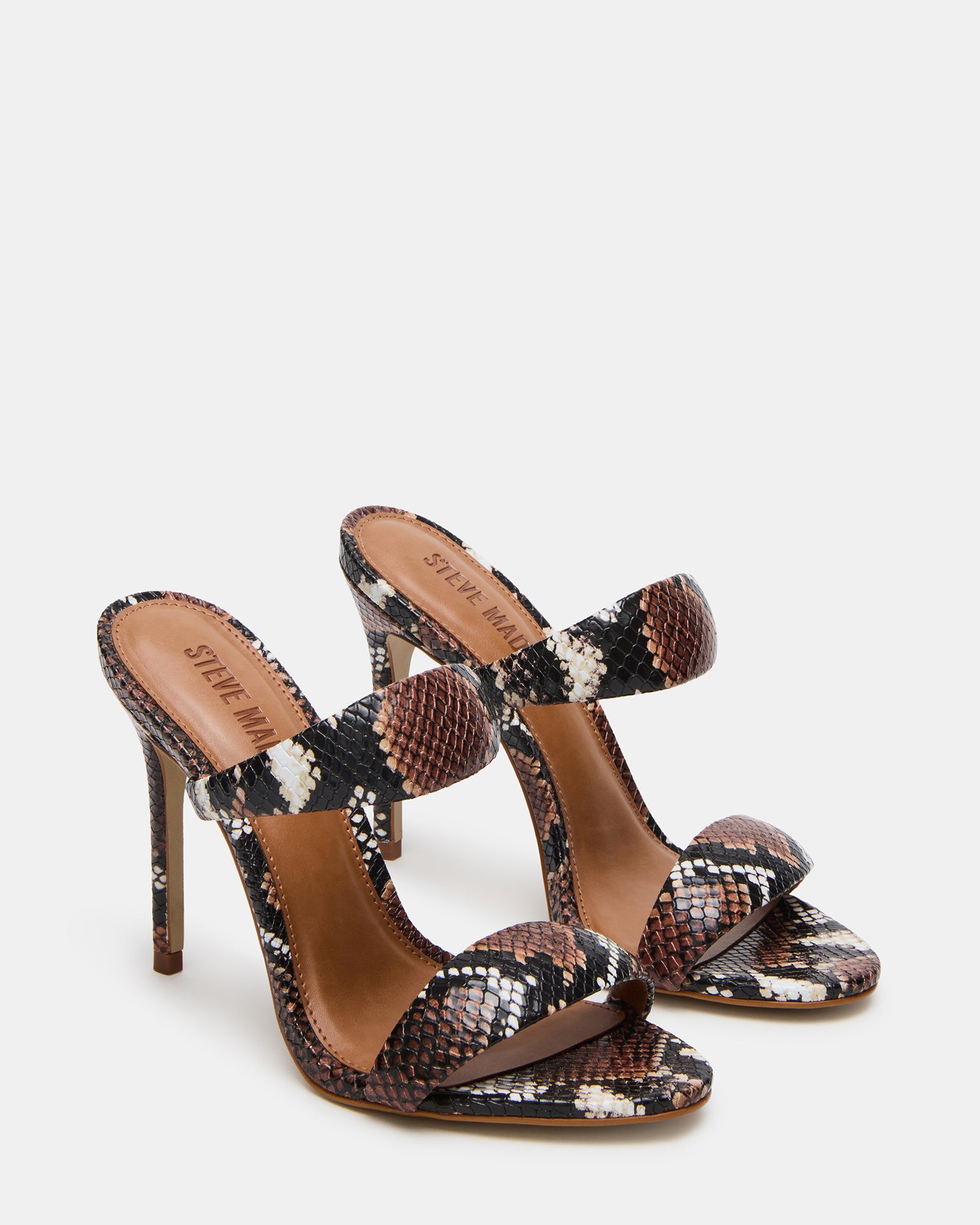 Model wearing high heel brown mule heels at a stylish event.