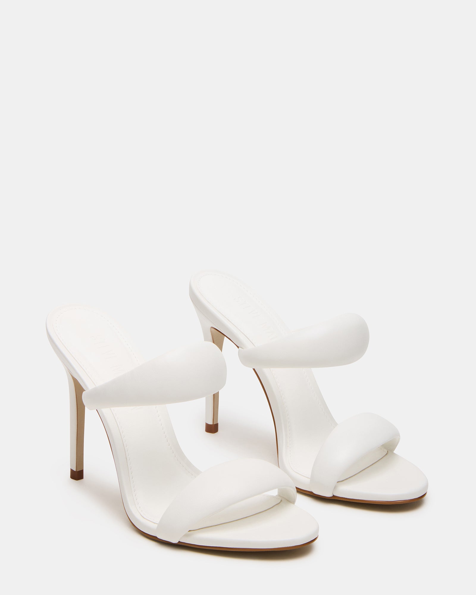 Model showcasing white kitten heels at a fashionable event.