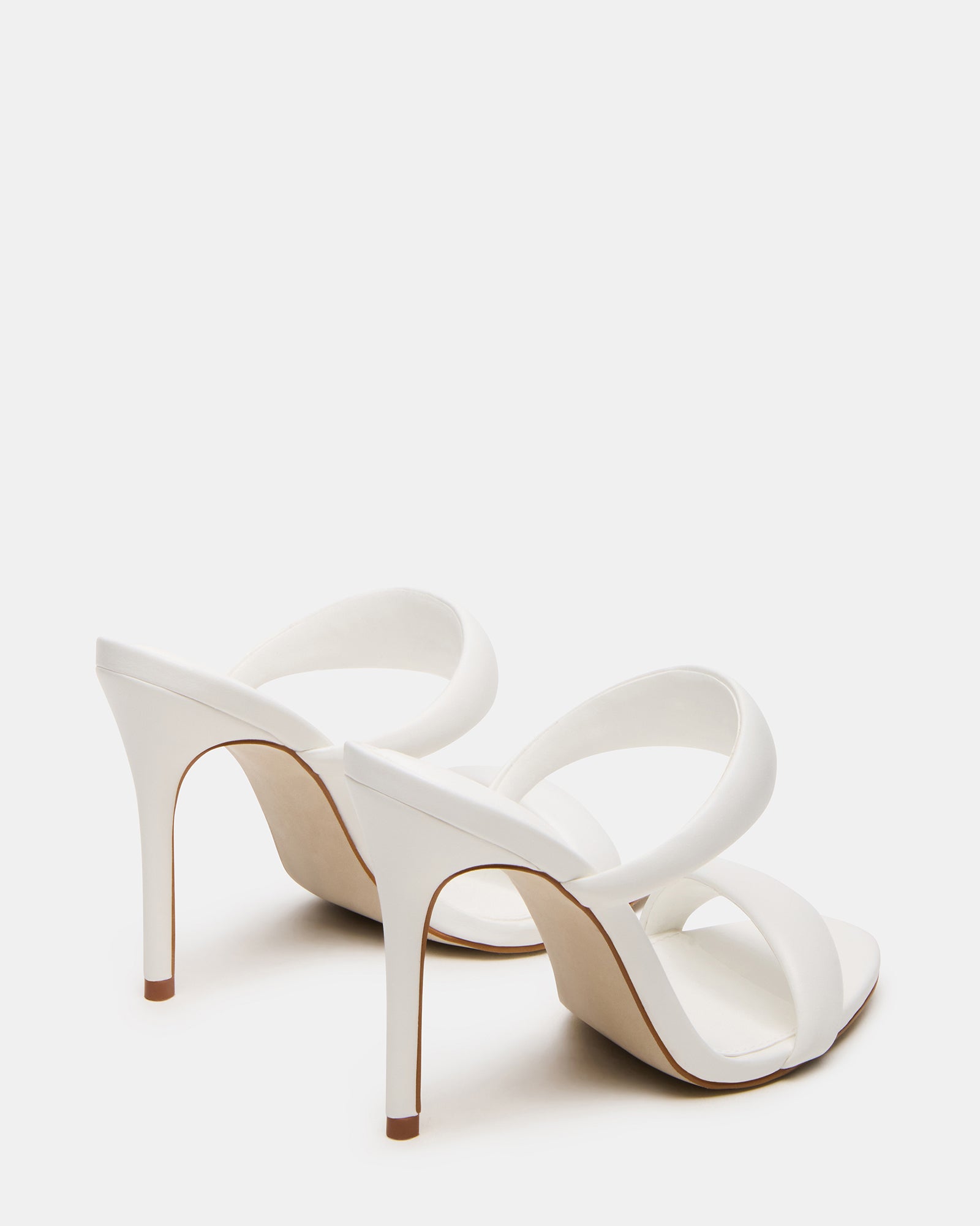 Model showcasing white kitten heels at a fashionable event.