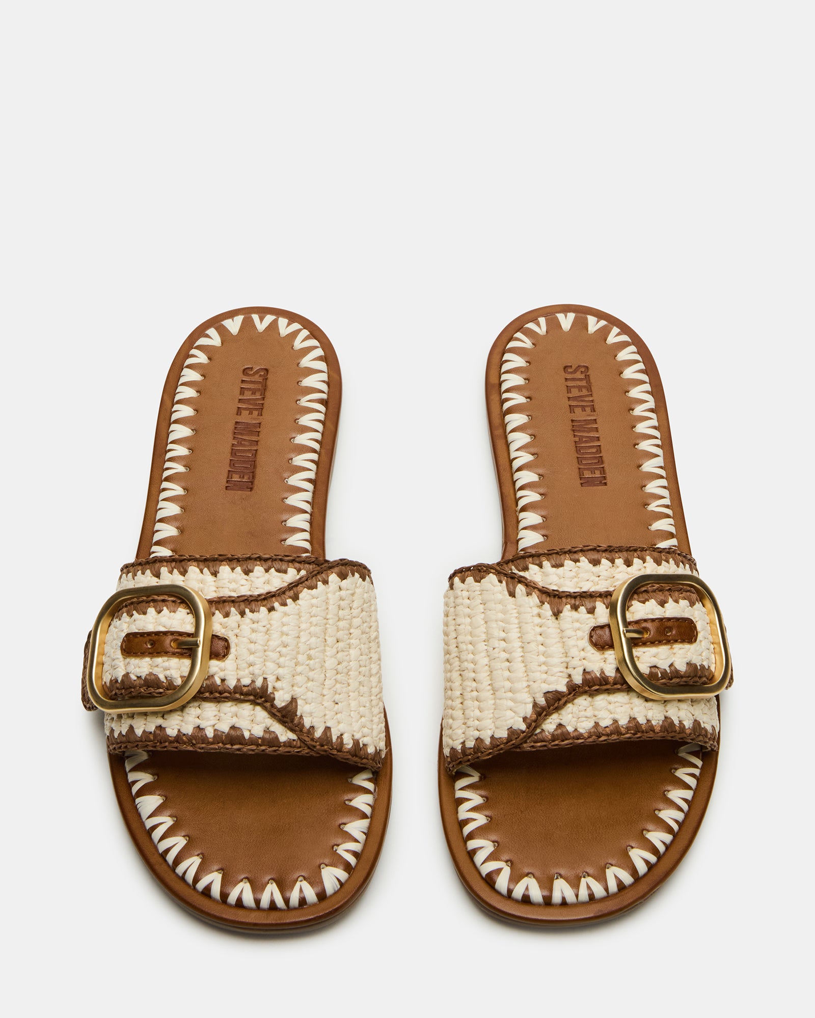 Close-up of buckle decal on tan raffia sandals, worn with cropped denim