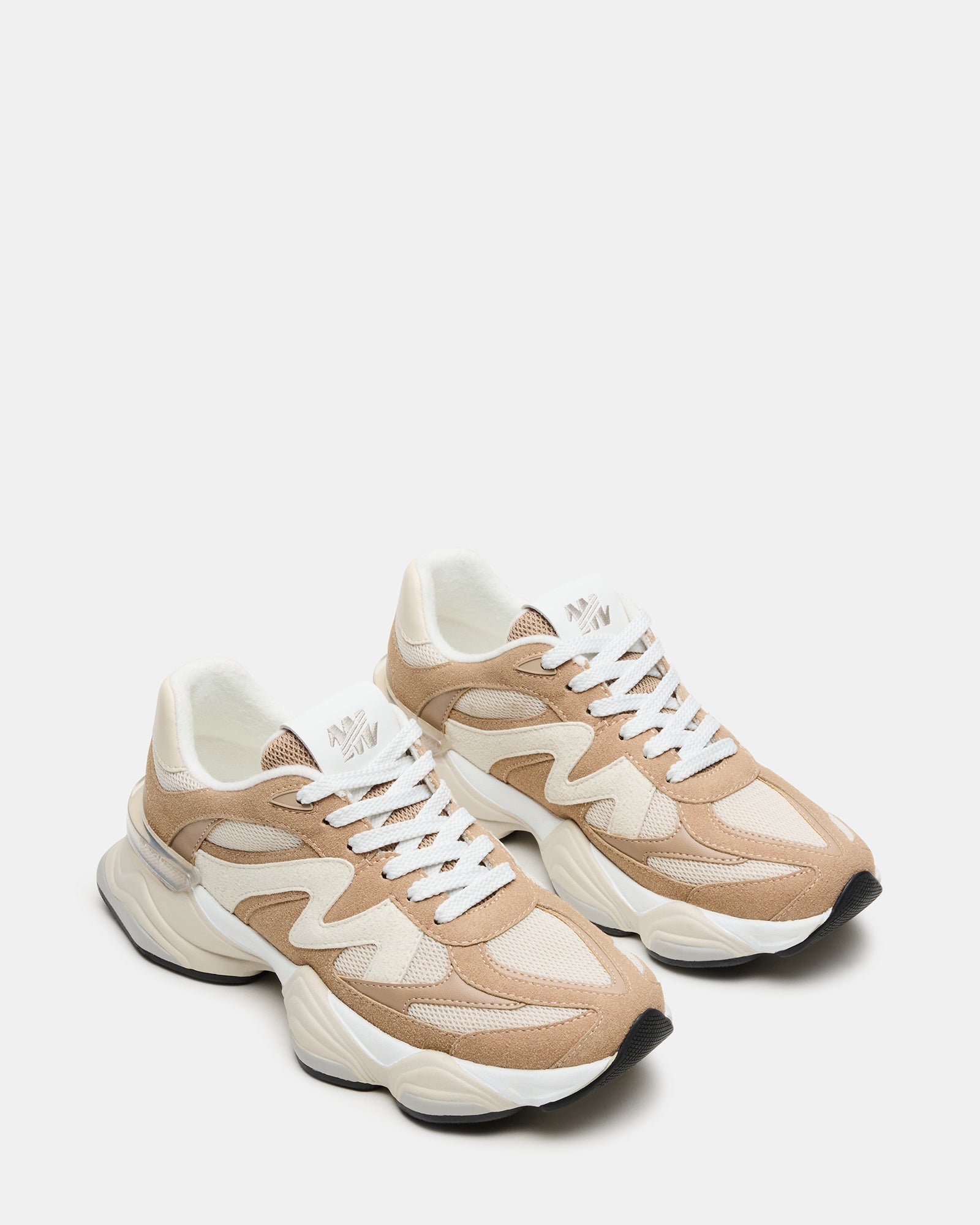 Model wearing taupe fashion sneakers in a casual outdoor setting, ideal for everyday wear.