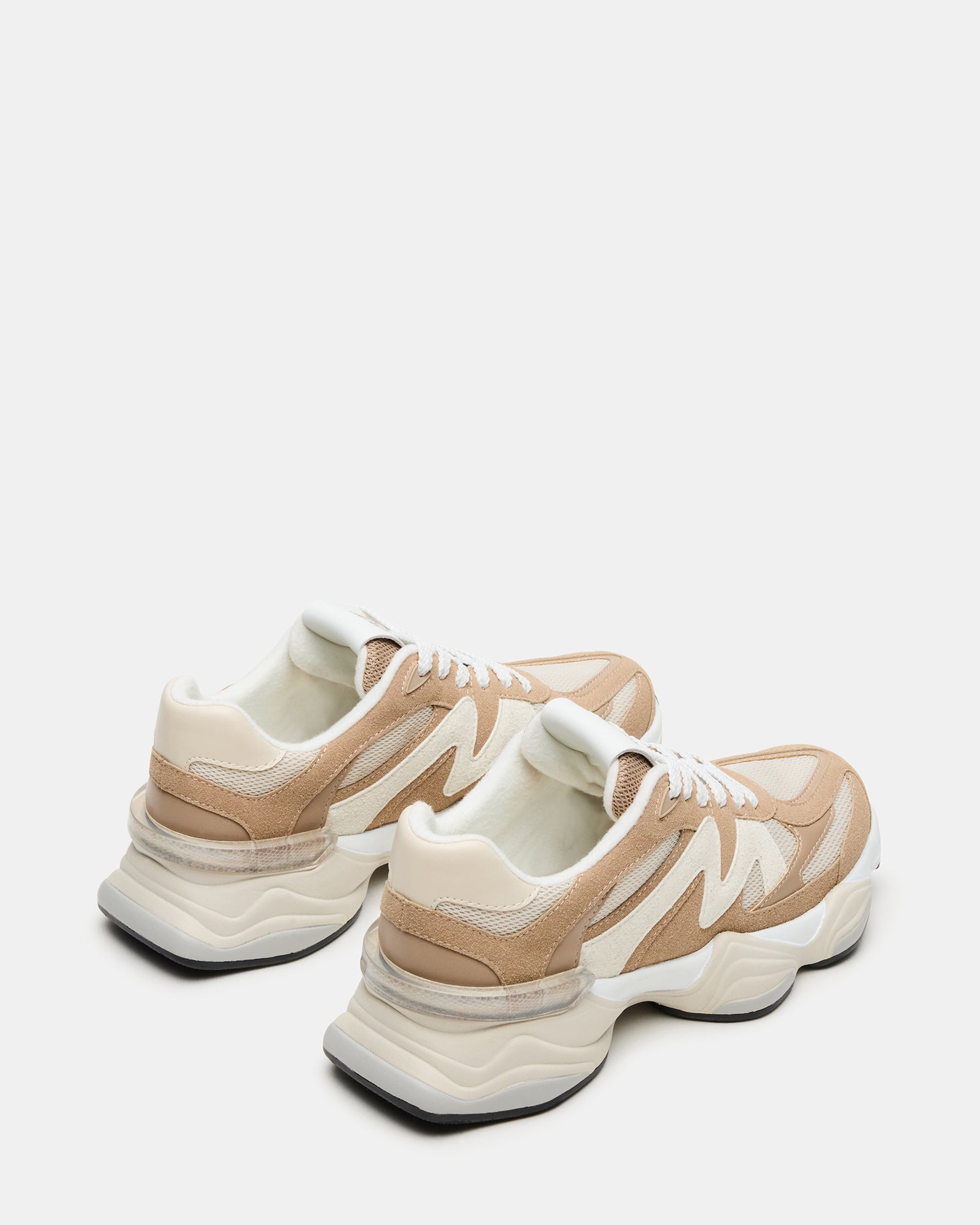 Model wearing taupe fashion sneakers in a casual outdoor setting, ideal for everyday wear.