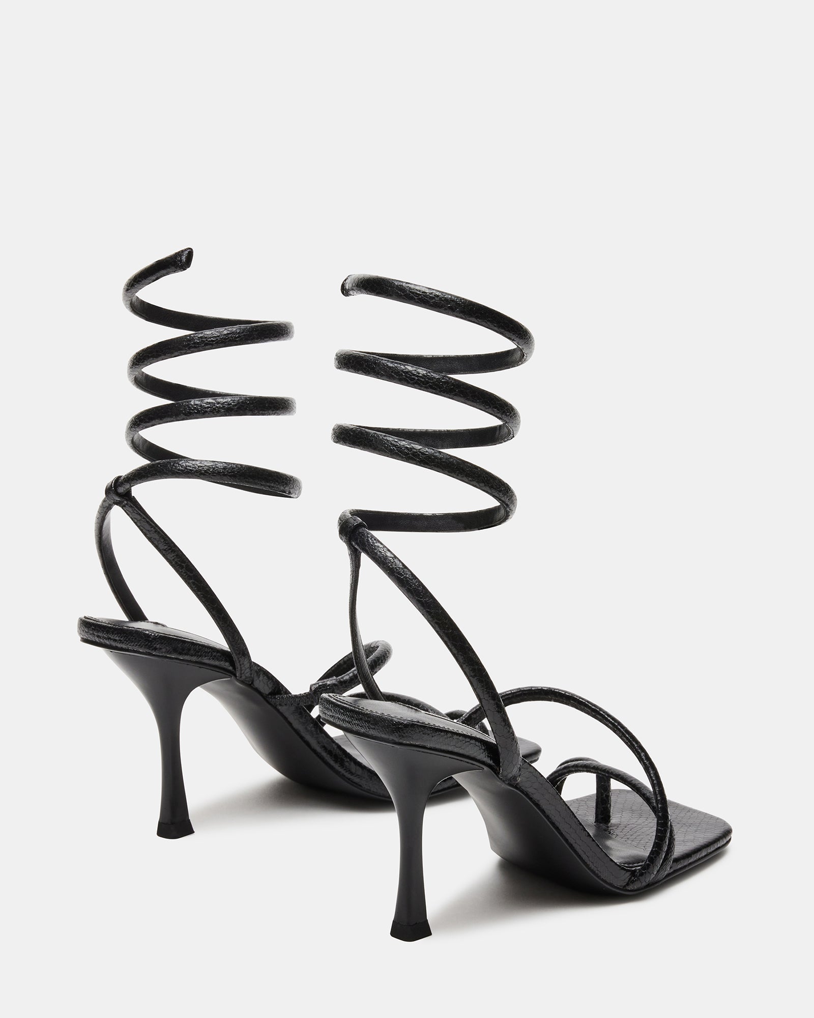 Black square toe stiletto sandal with coil ankle strap on a chic model