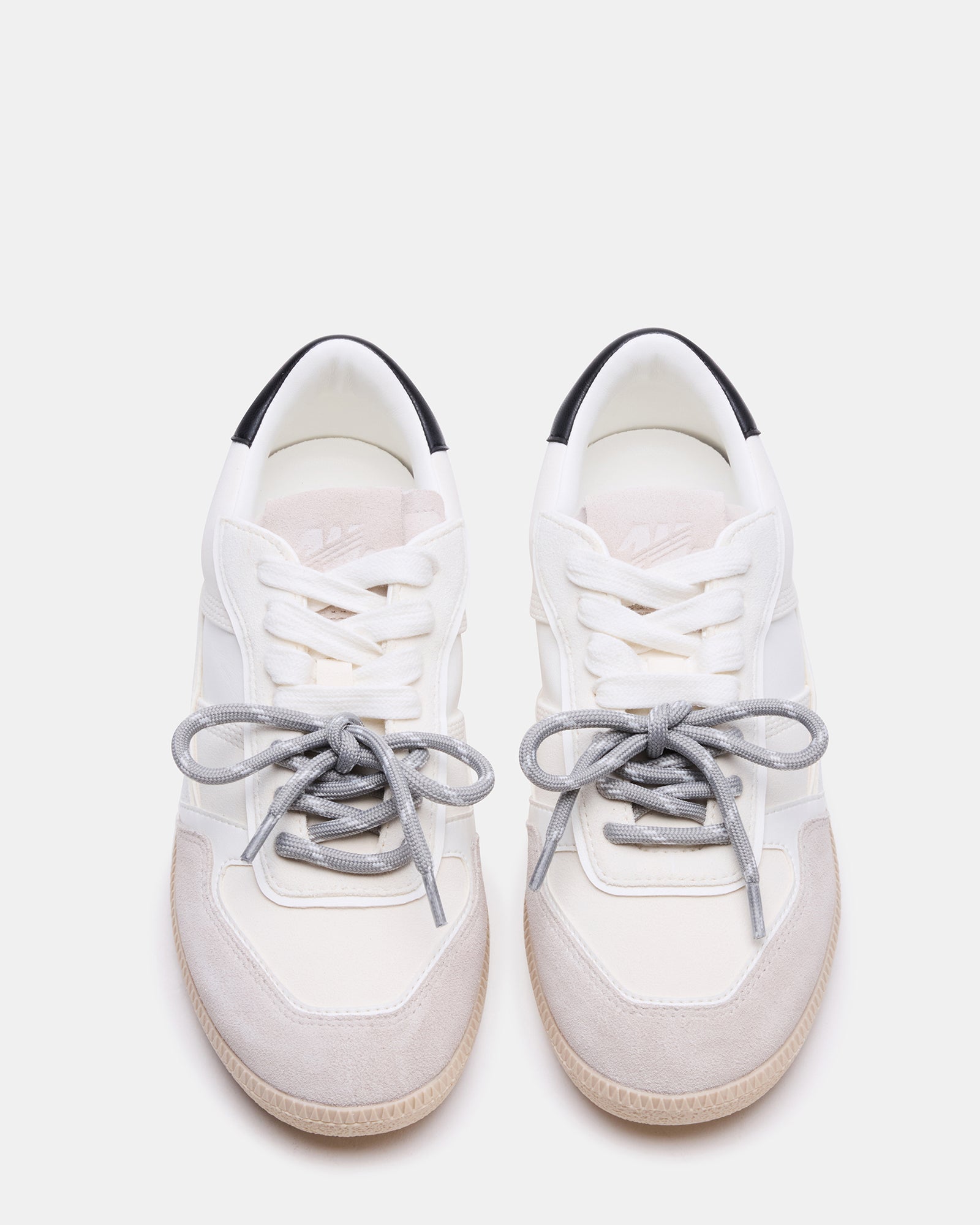 Side view of white mens sneakers with striped laces on concrete