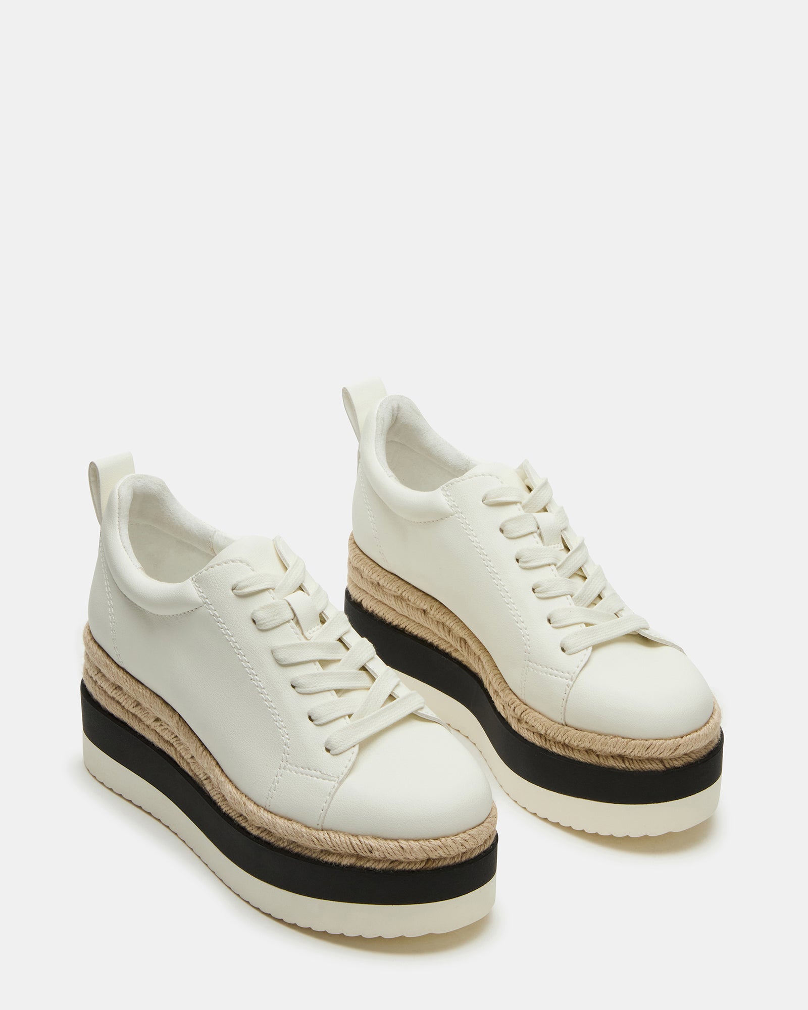 White leather sneakers paired with casual wear outdoors.