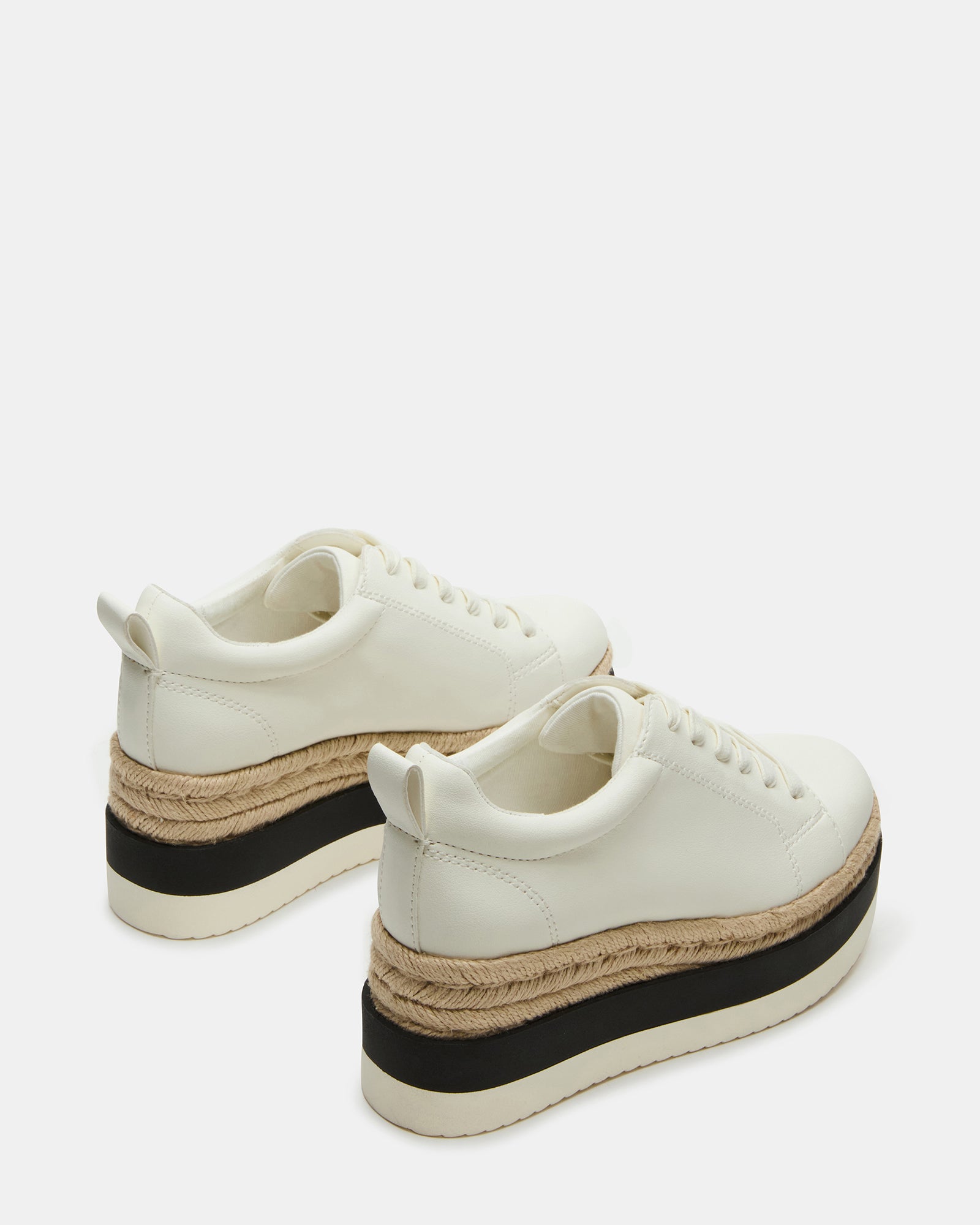 White leather sneakers paired with casual wear outdoors.