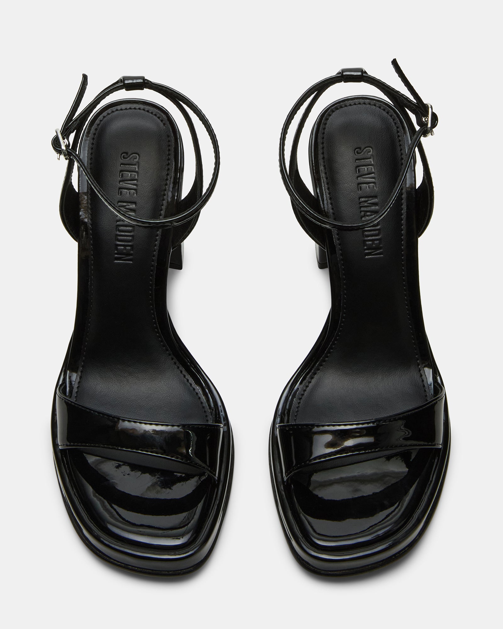 Close-up of black strappy sandals showing square toe and glossy finish
