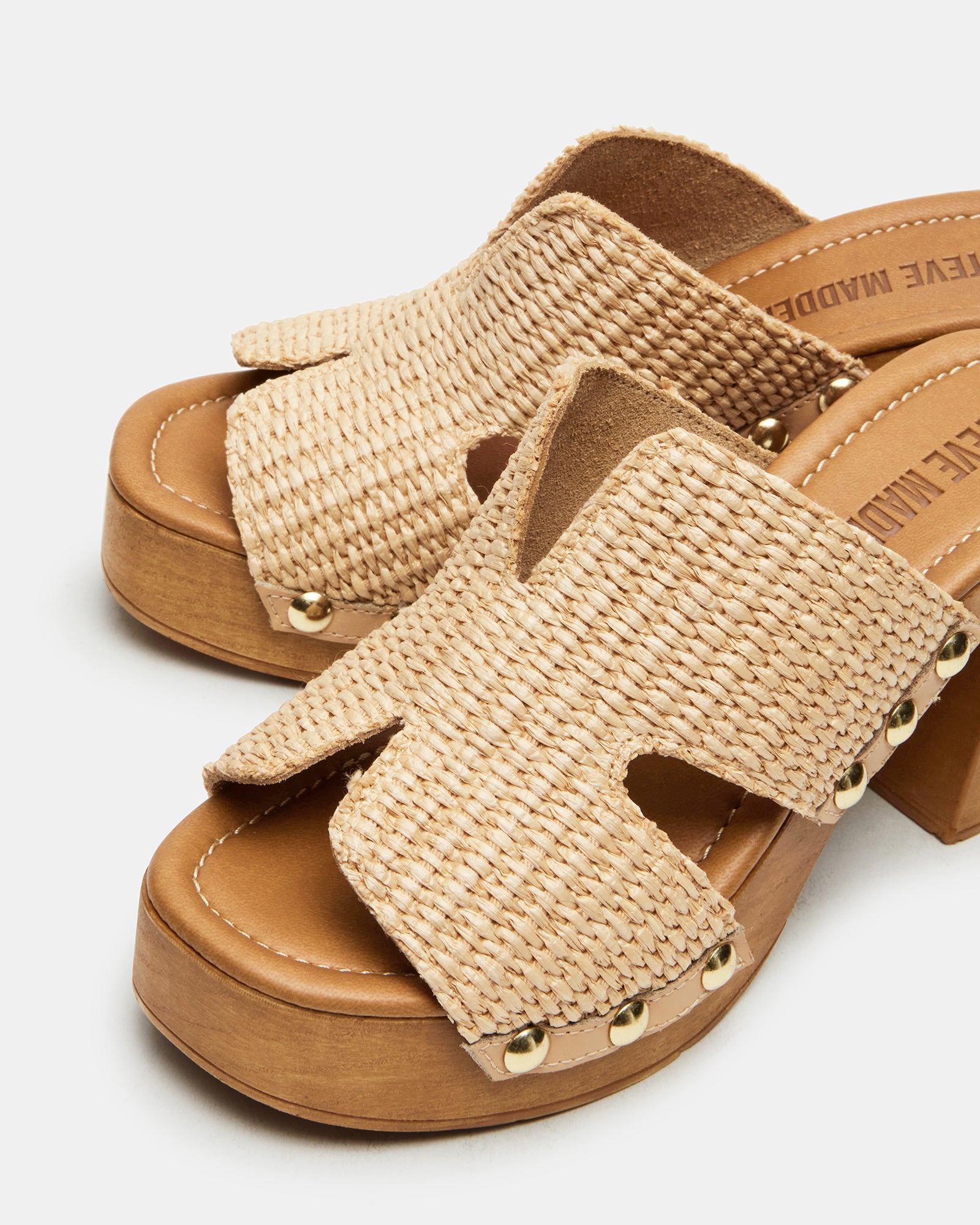 Close-up of raffia platform sandals with stud details on a sunny patio