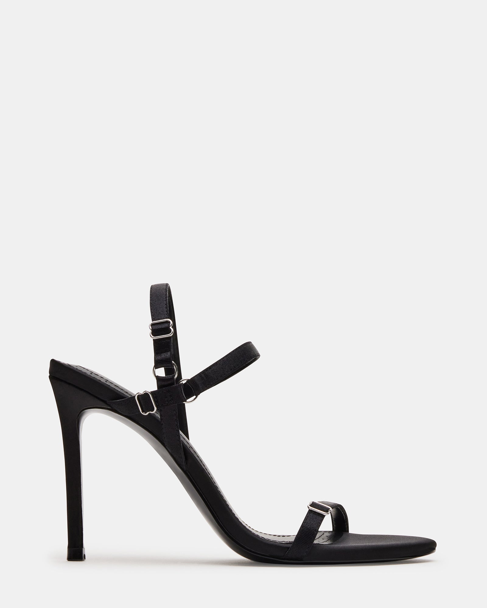 Side view of black stiletto heels with open toe on marble surface