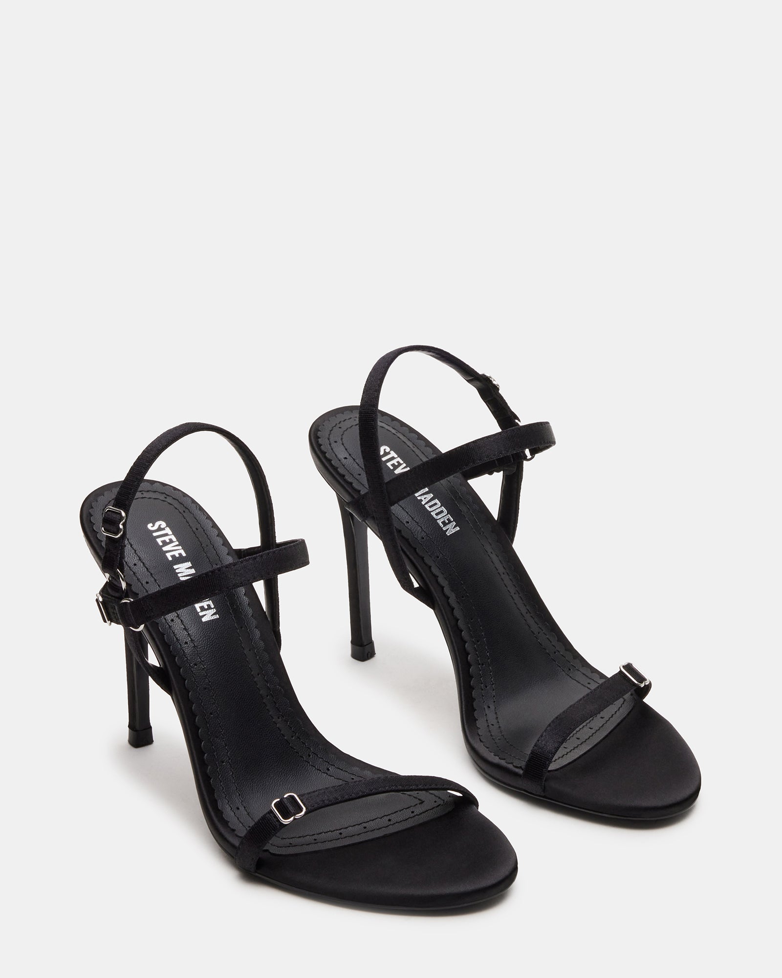 Close-up of satin straps and heel silhouette on black platform heels