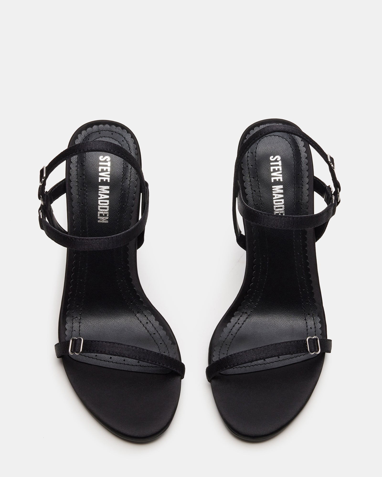 Side view of black stiletto heels with open toe on marble surface