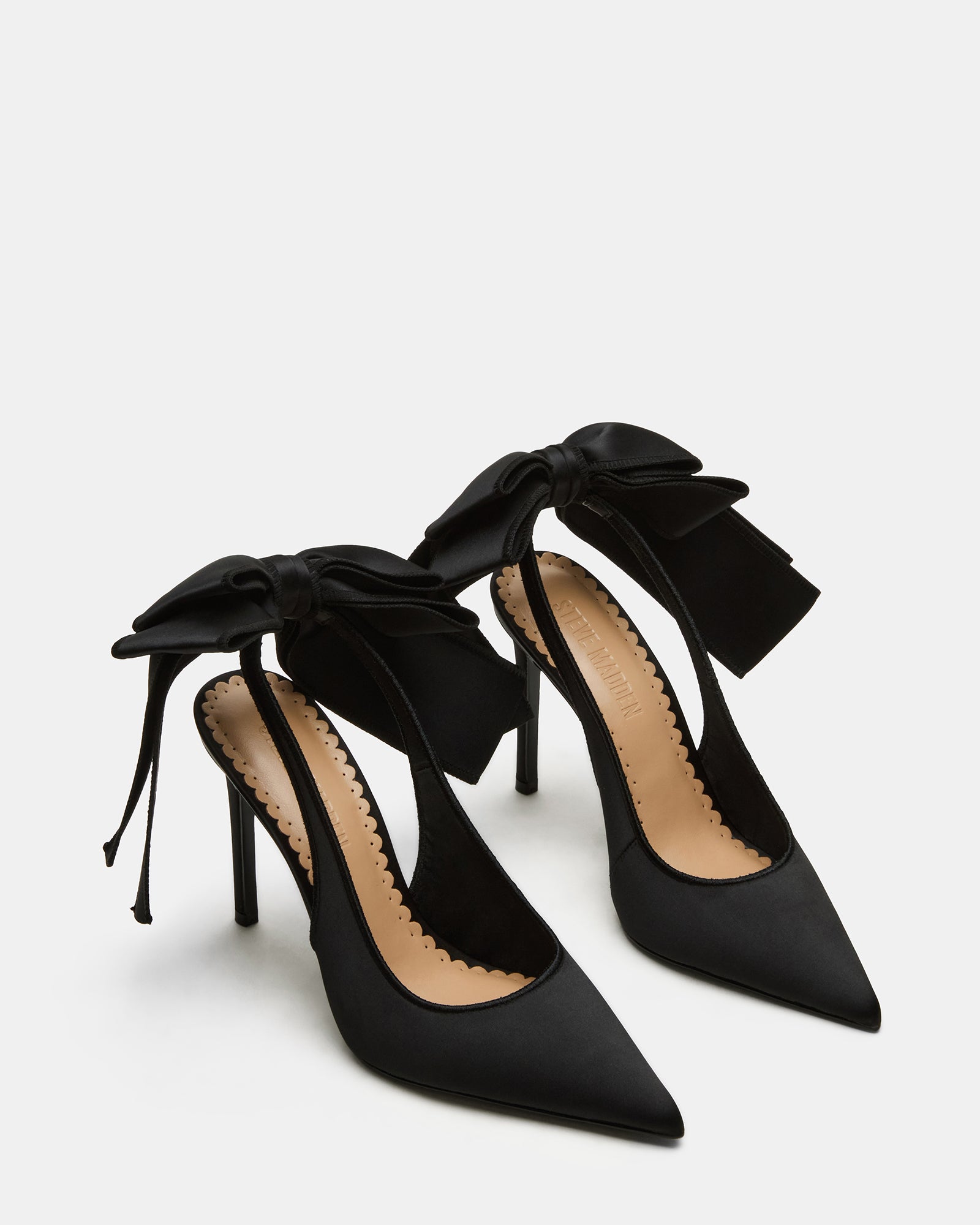 Model wearing the Teacup black satin heels in an urban setting.