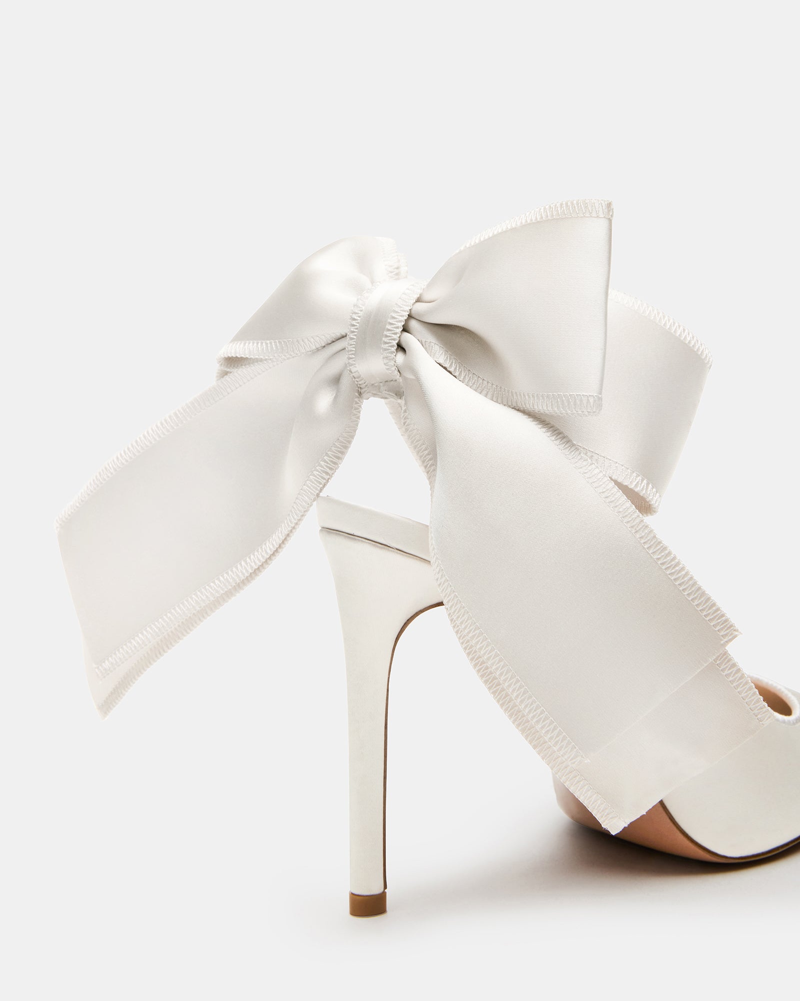 Close-up of ivory satin slingback heels with pointed toe and bow