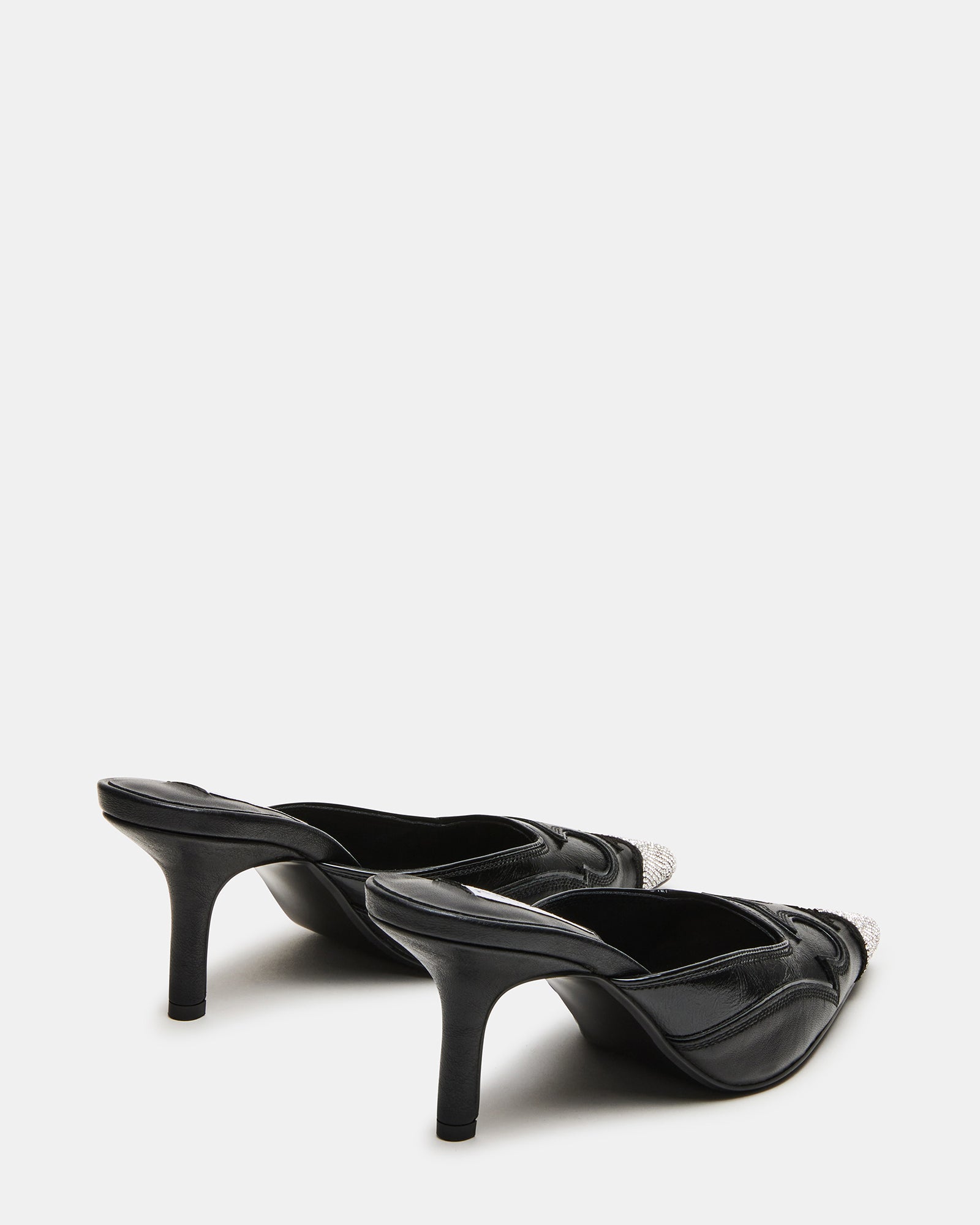 Close-up of the pointed toe of black mule shoes with rhinestone detailing.