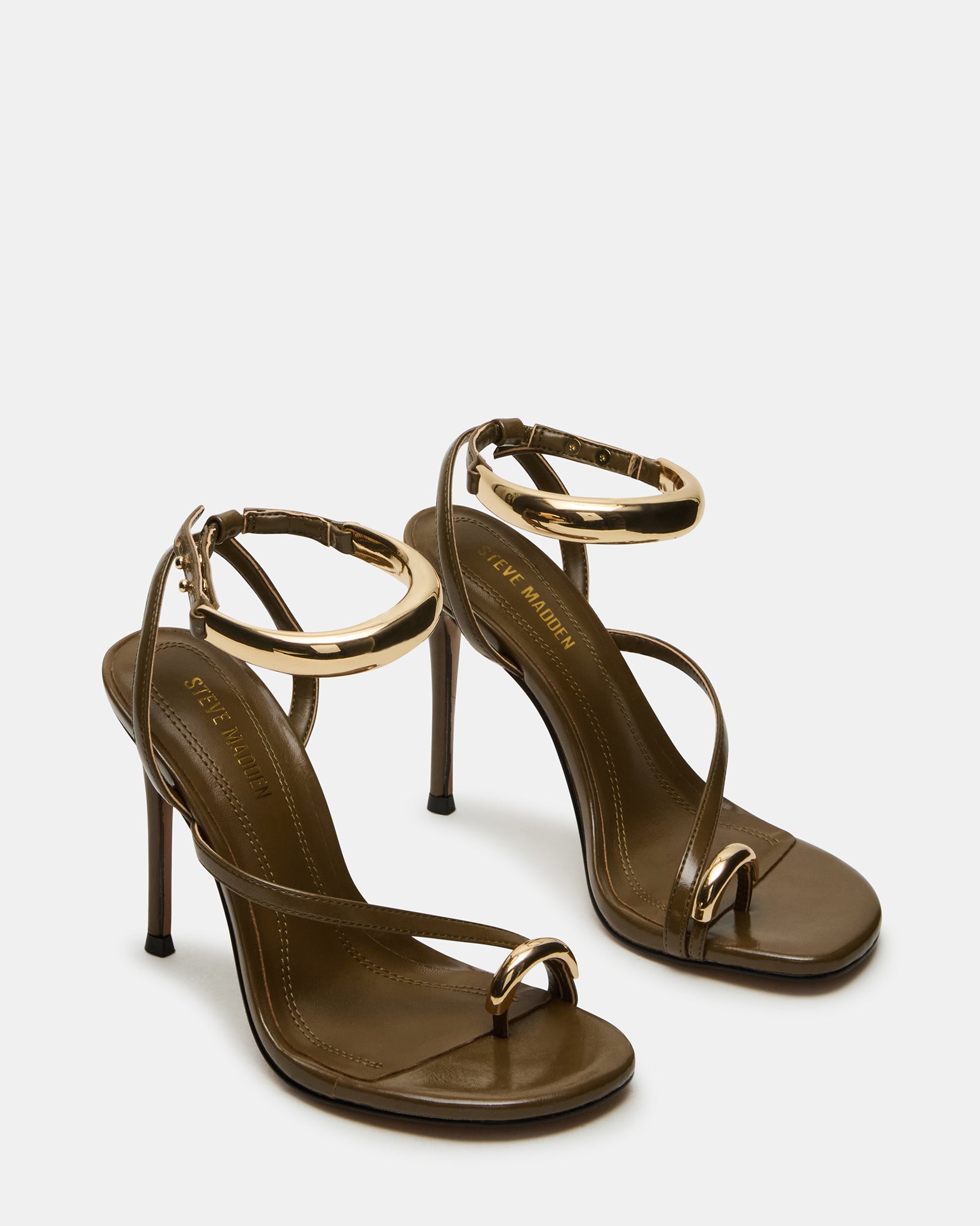 Front view of gold stiletto heels highlighting the unique hardware.