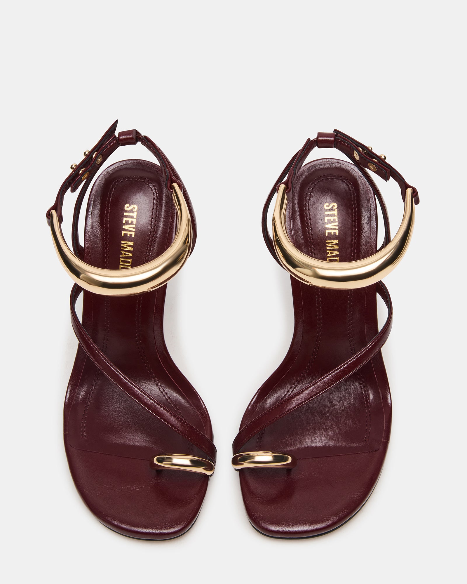 Gold strappy stiletto heels on a marble background