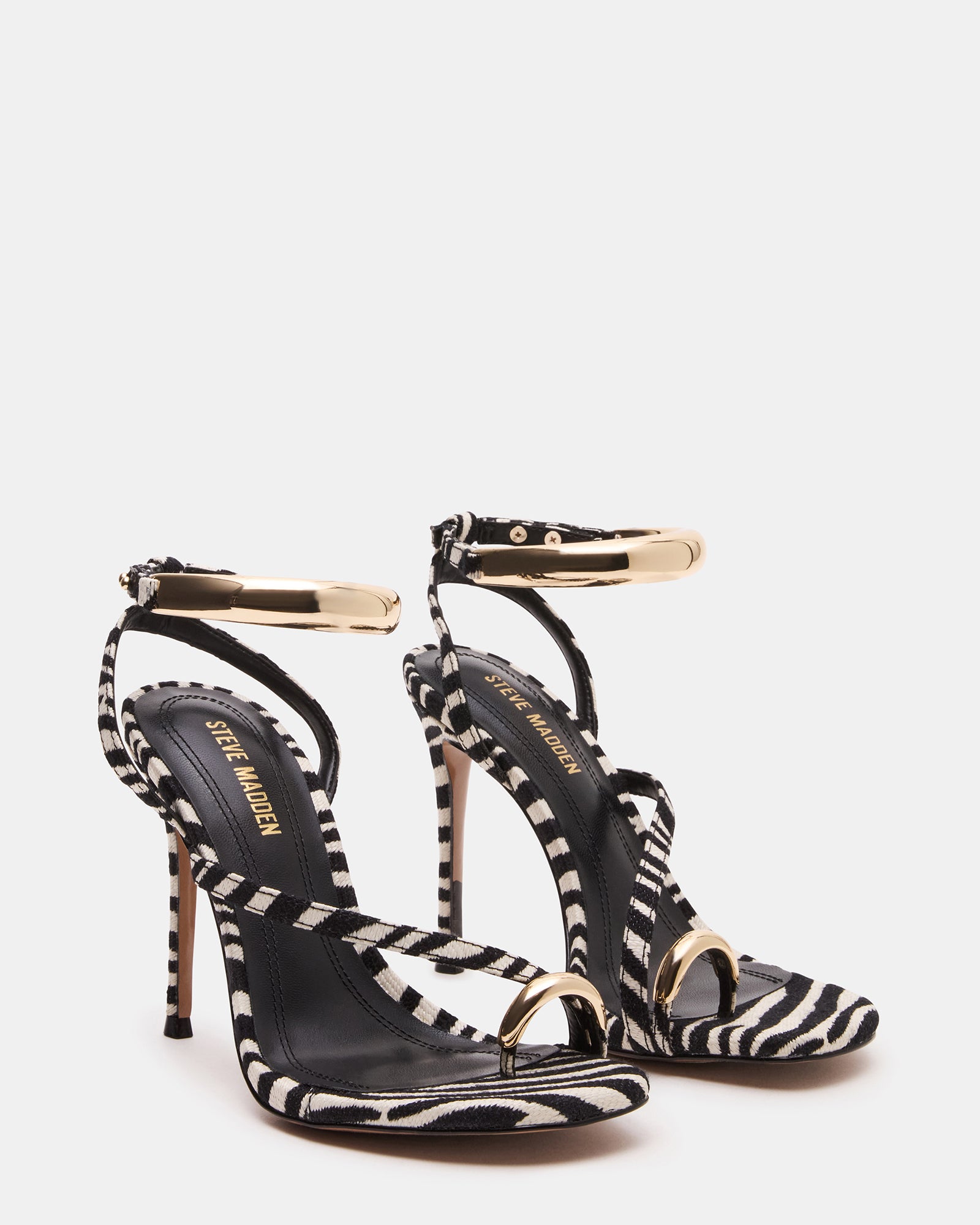 Full view of gold strappy heels worn with a stylish outfit, ideal for nightlife.
