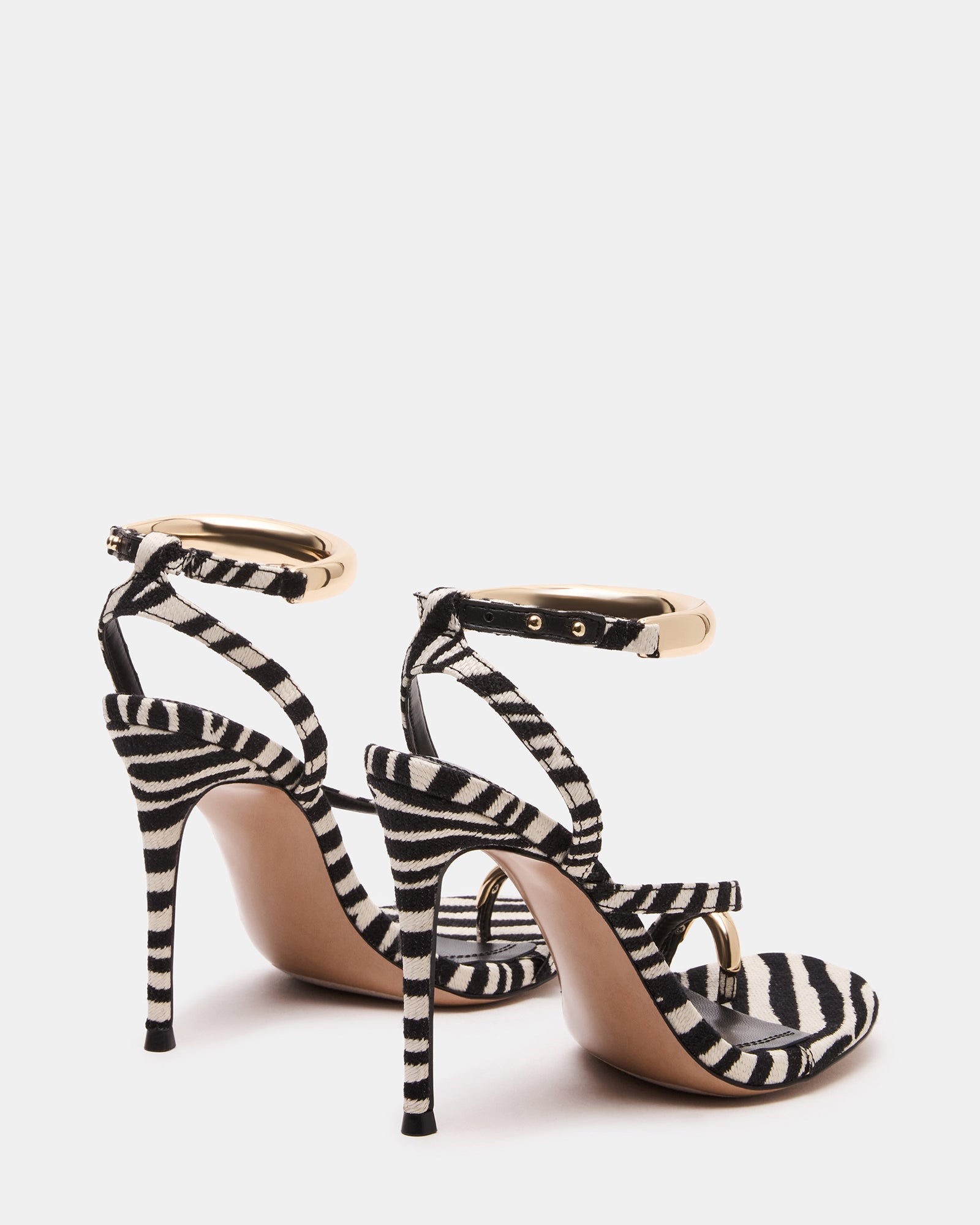 Full view of gold strappy heels worn with a stylish outfit, ideal for nightlife.