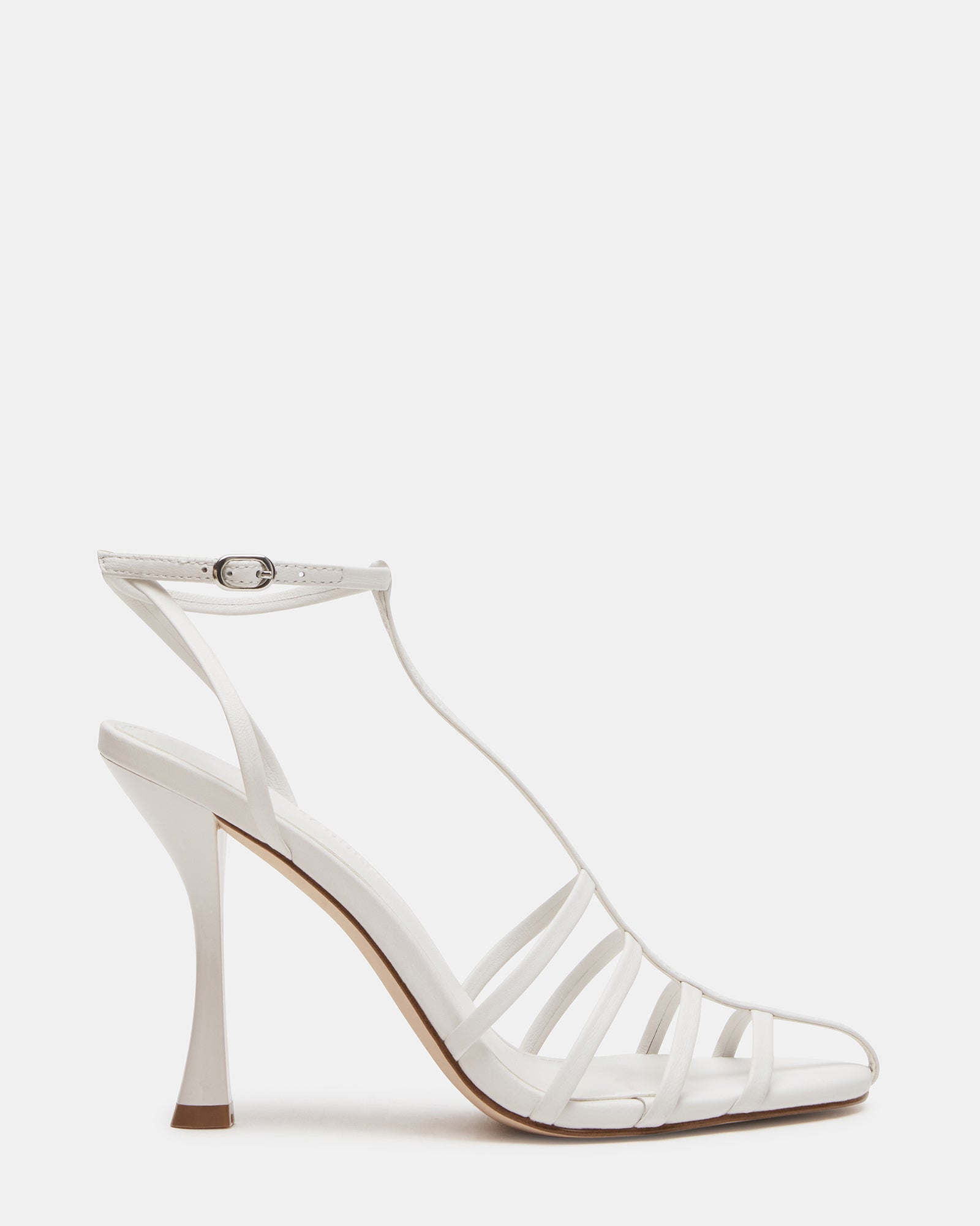 Side profile of white leather heels with ankle and t-strap, worn during a city night out