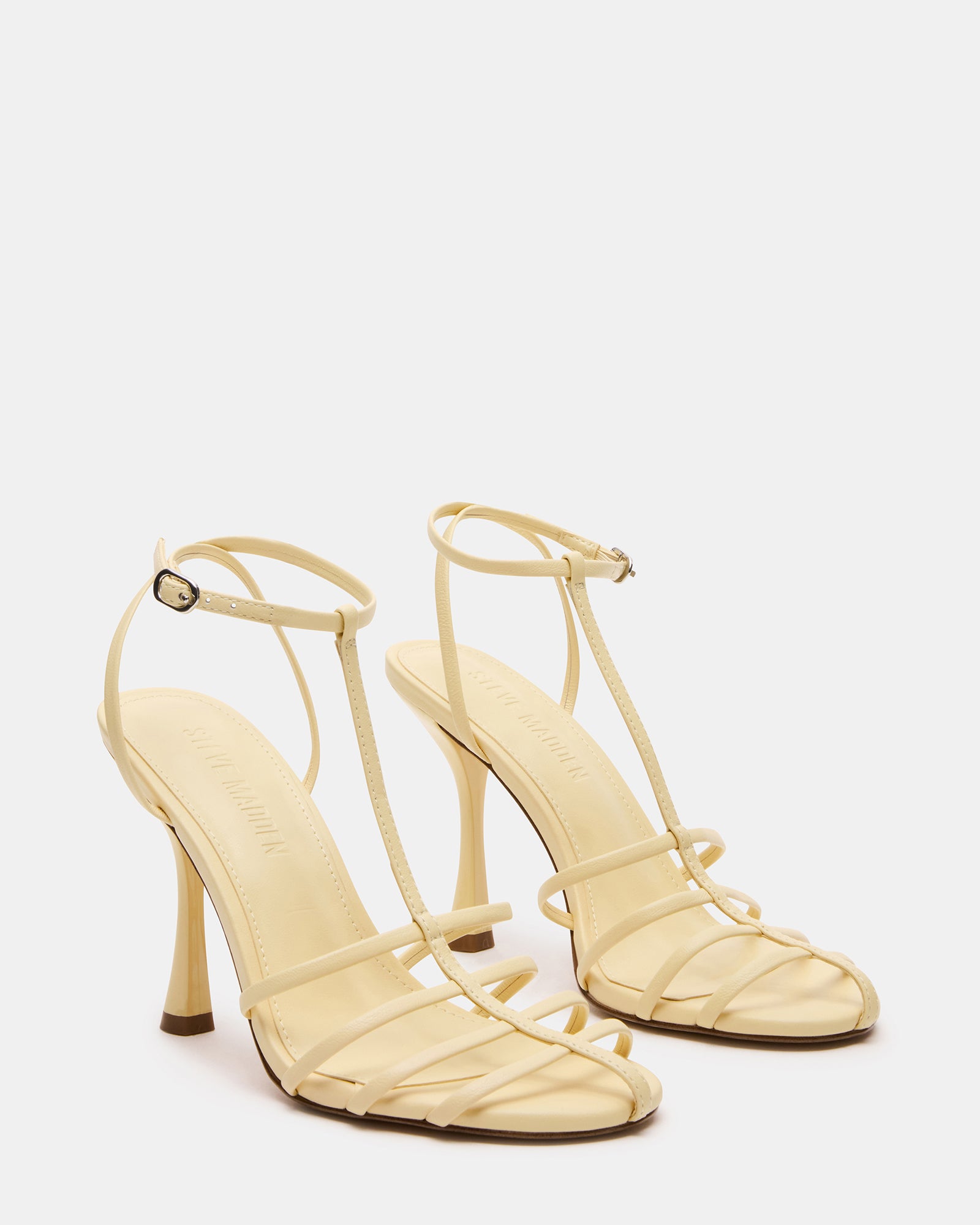 Side profile of black leather heels showcasing T-strap design in natural light