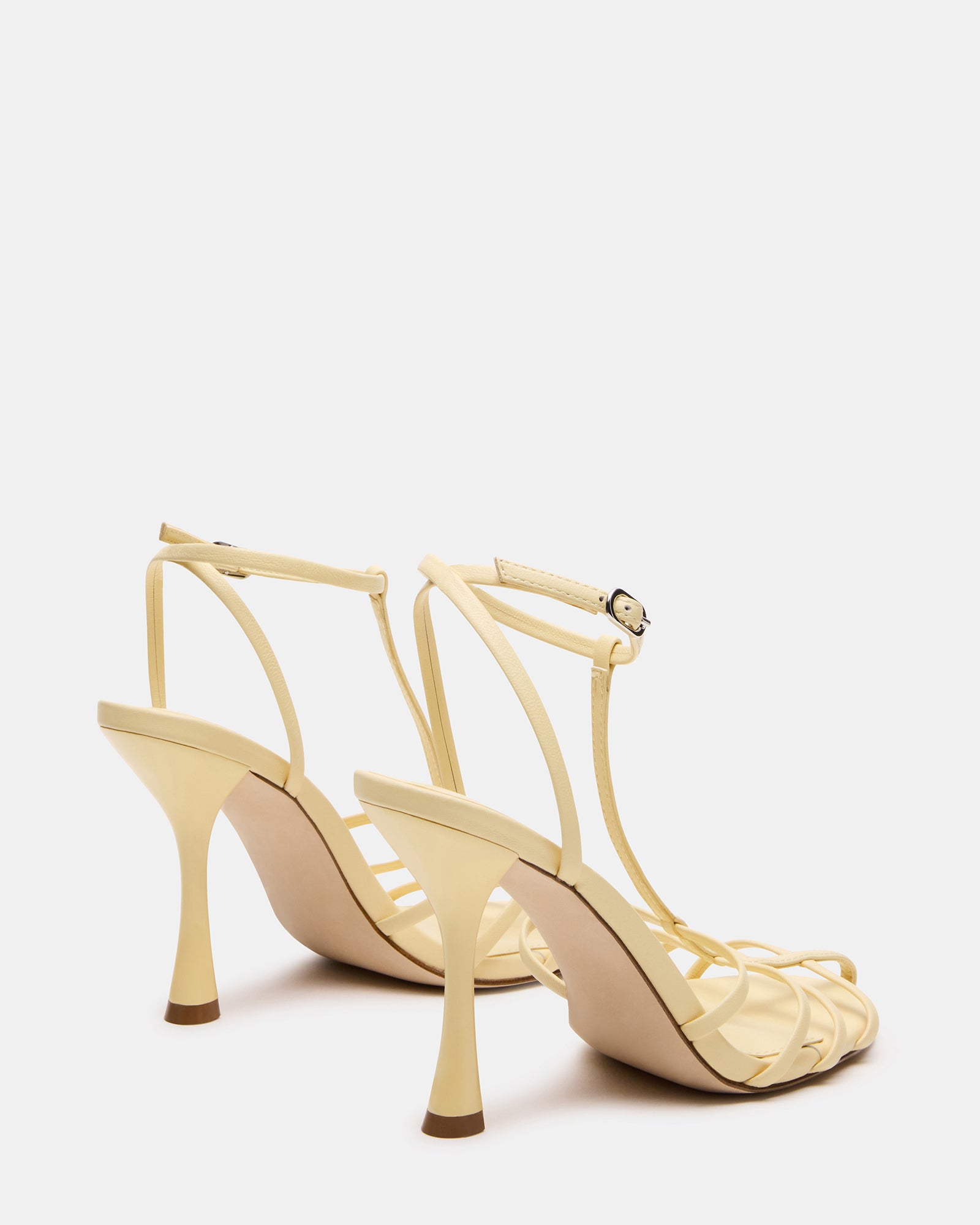 Side profile of black leather heels showcasing T-strap design in natural light