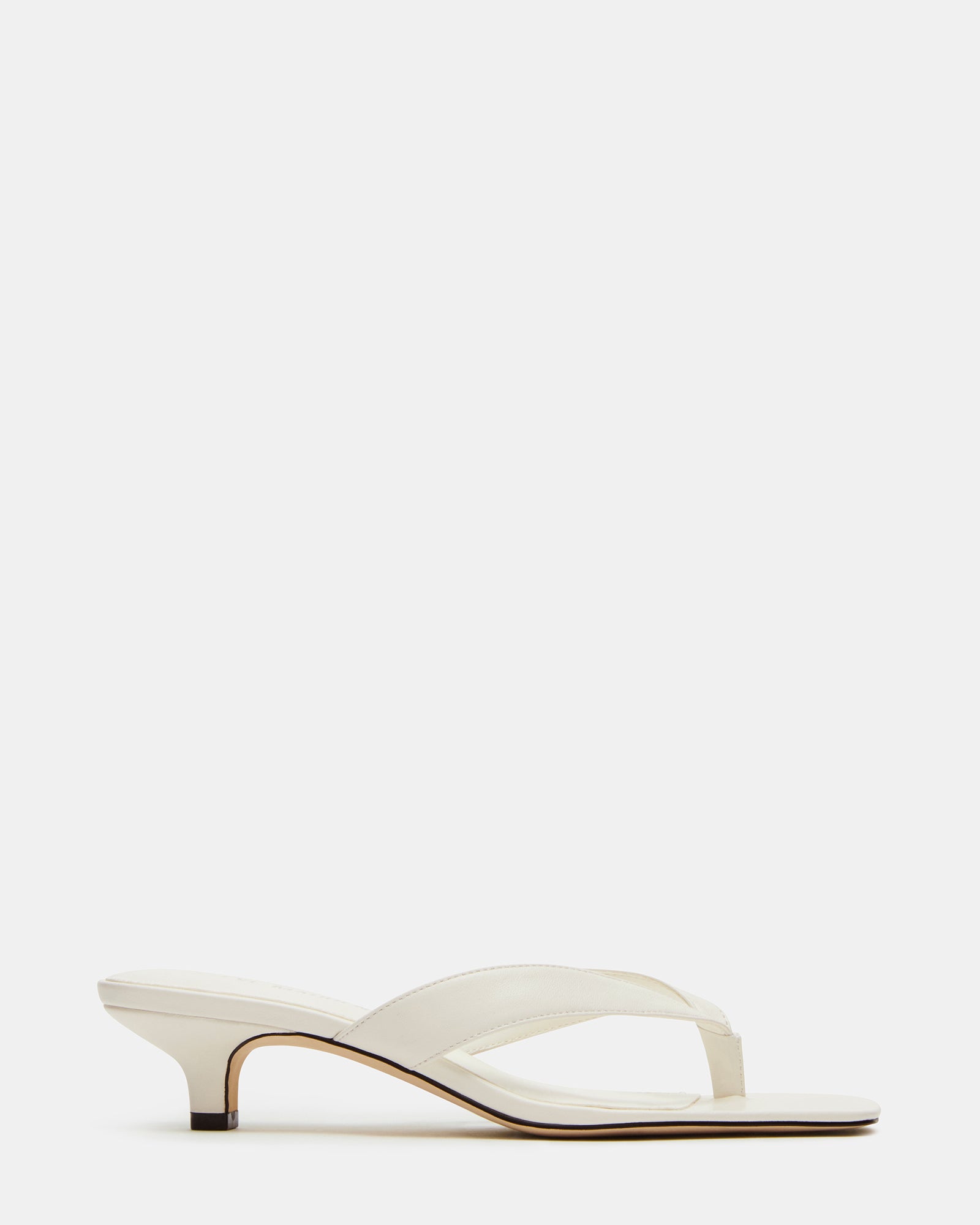 White leather shoes with kitten heels and thong strap, styled for formal occasions