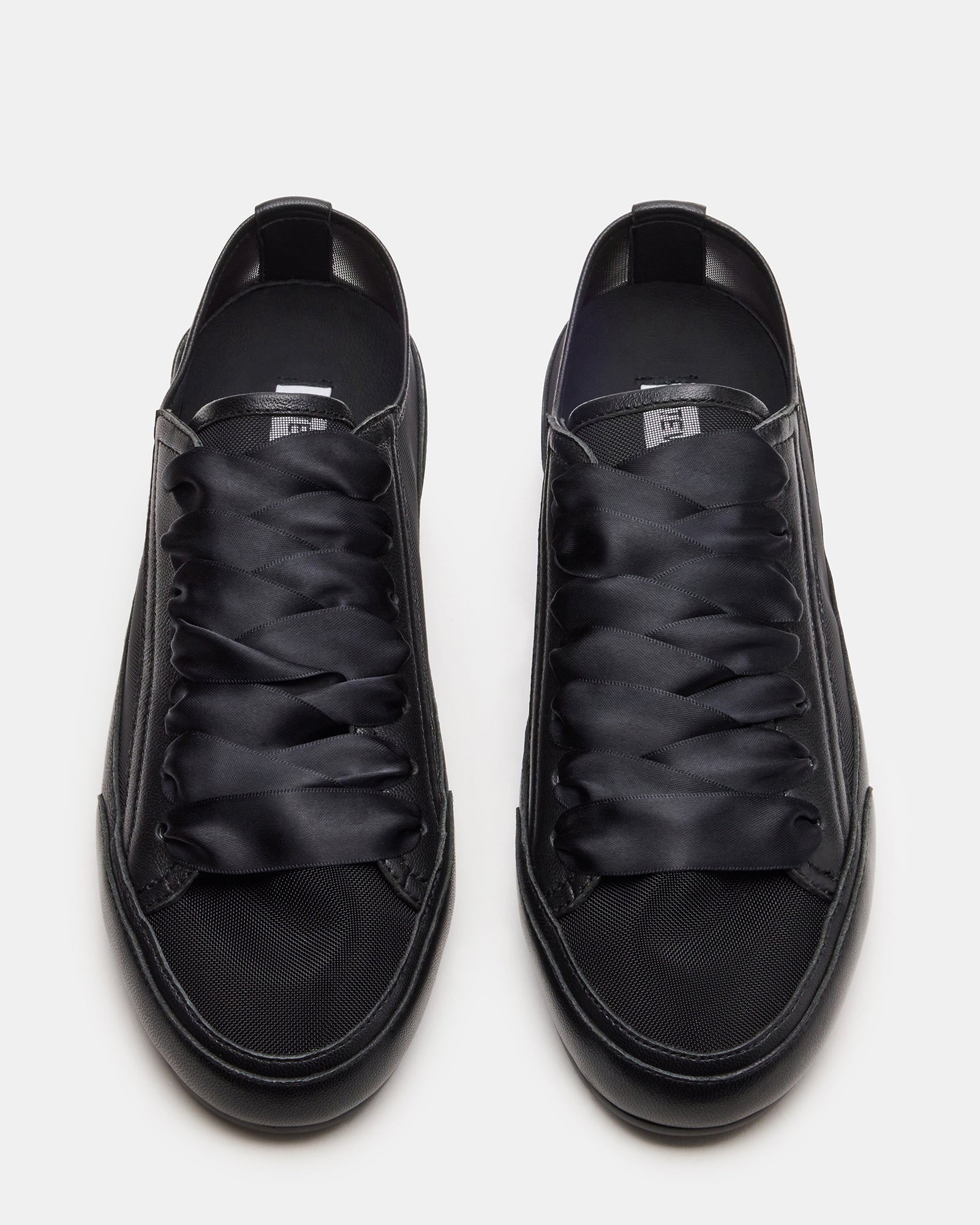 Side view of TREAD black leather sneakers featuring ribbon laces.