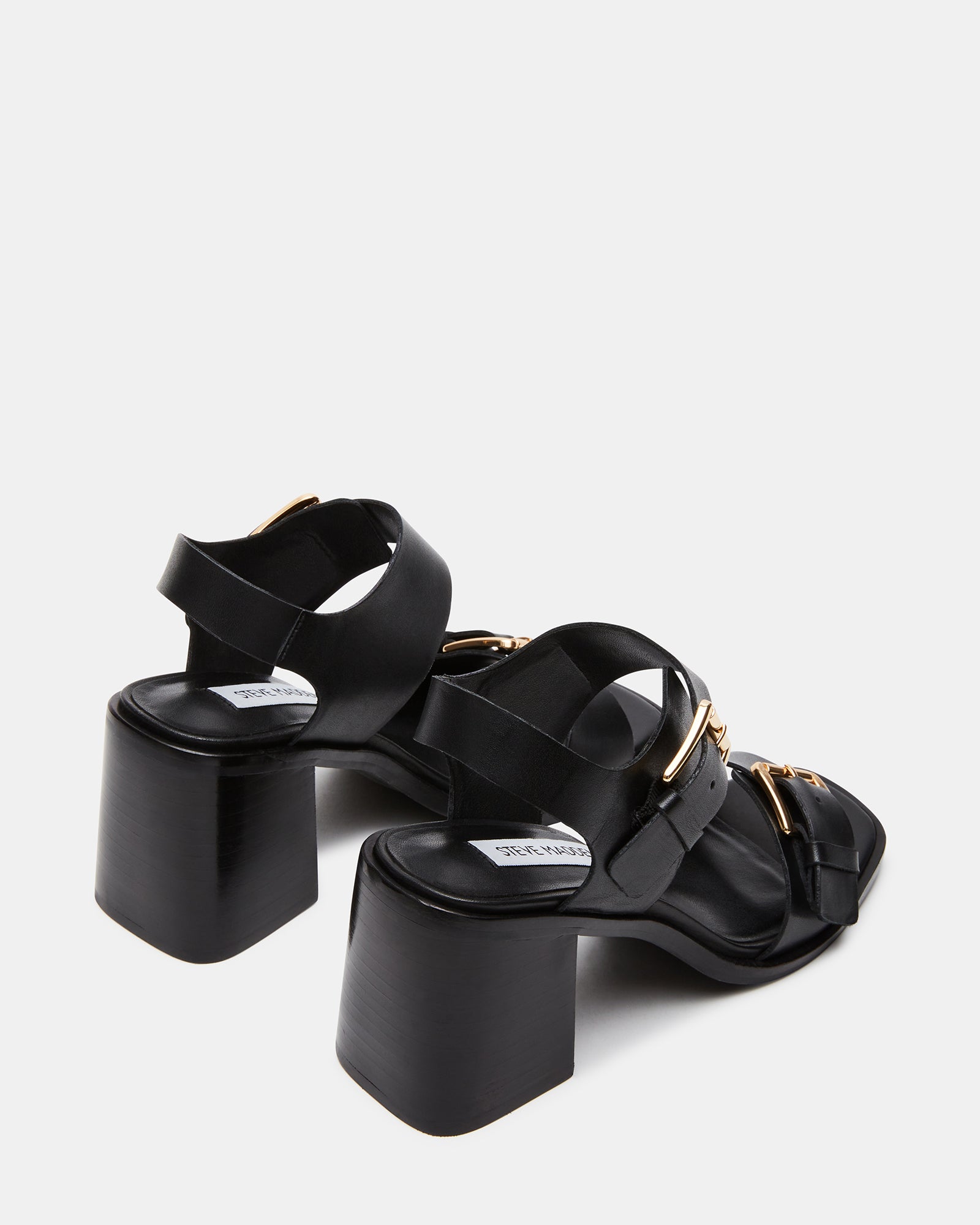 Model wearing black block heel sandals at a casual outdoor event.