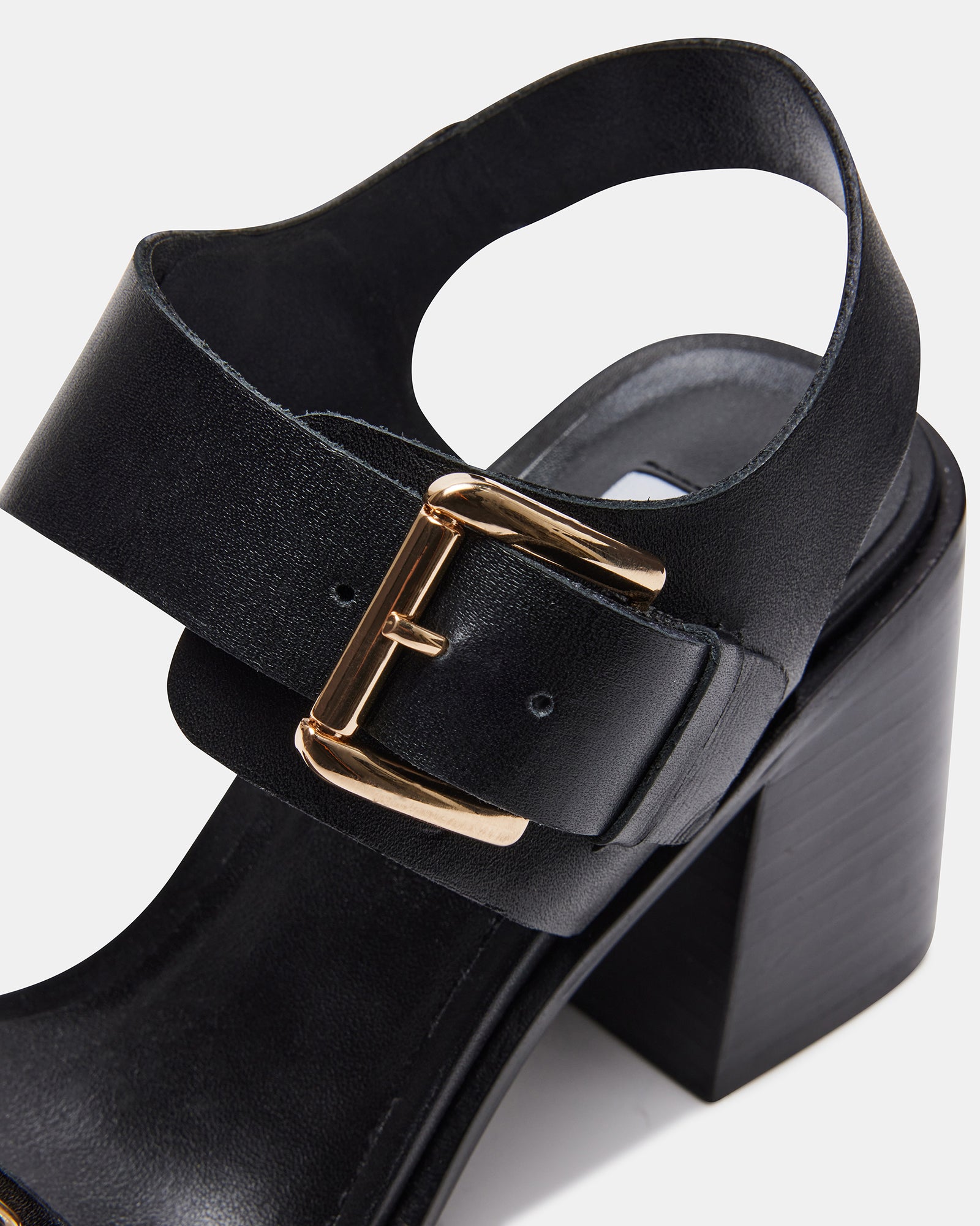 Model wearing black block heel sandals at a casual outdoor event.