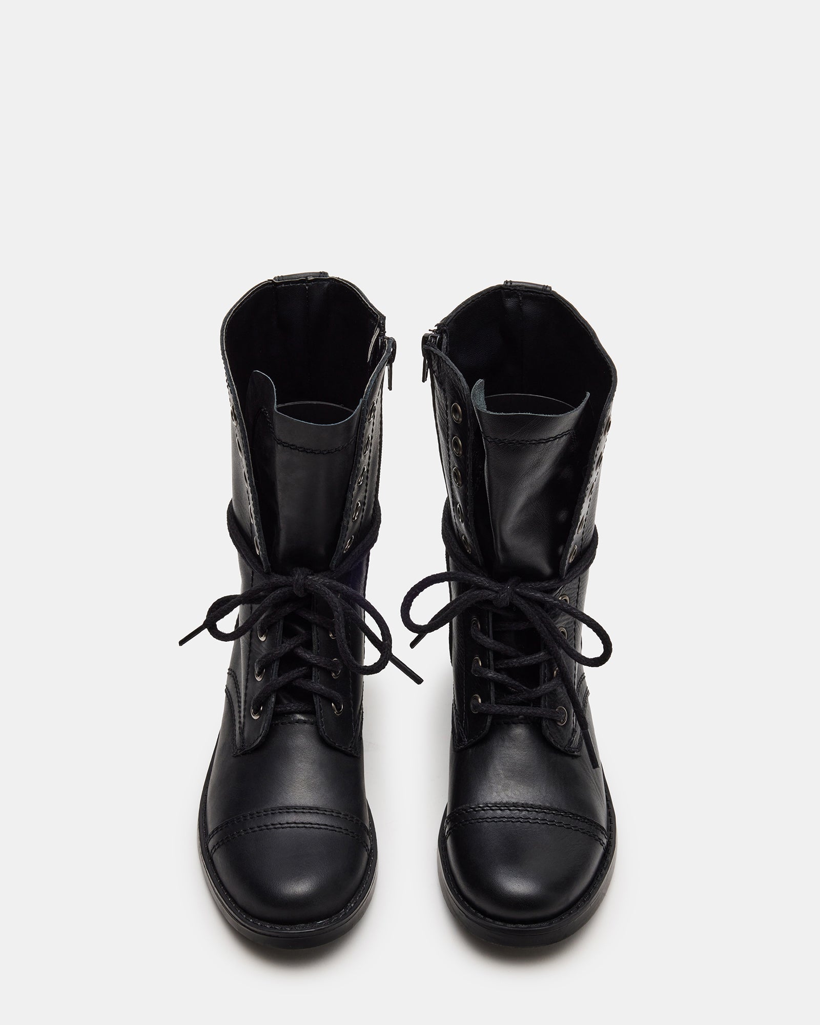 Model wearing black combat boots with rolled jeans in urban setting