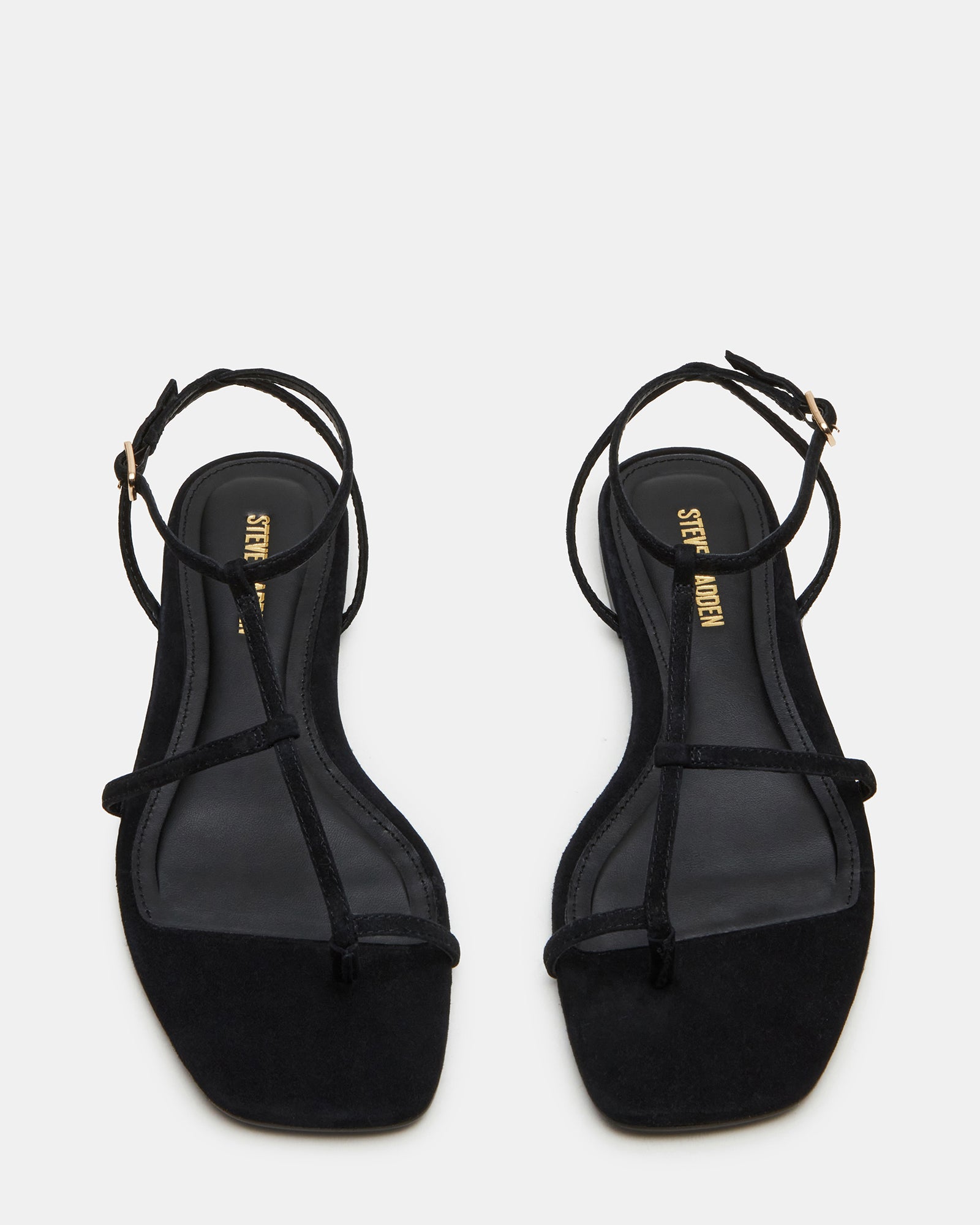 Side view of black suede sandals with flat sole and strappy design on model