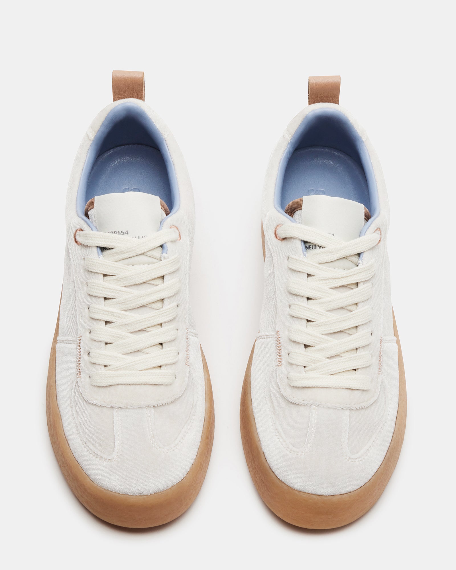 Close-up of the lace-up detail on the white sneakers, highlighting the vegan leather lining.