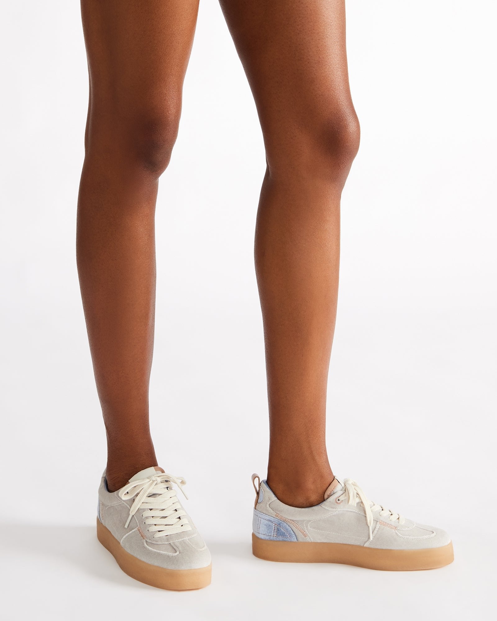 Close-up of the lace-up detail on the white sneakers, highlighting the vegan leather lining.