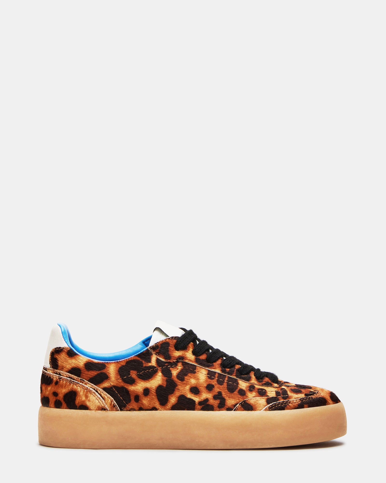 Side profile of white sneakers with leopard accents, shown with urban streetwear