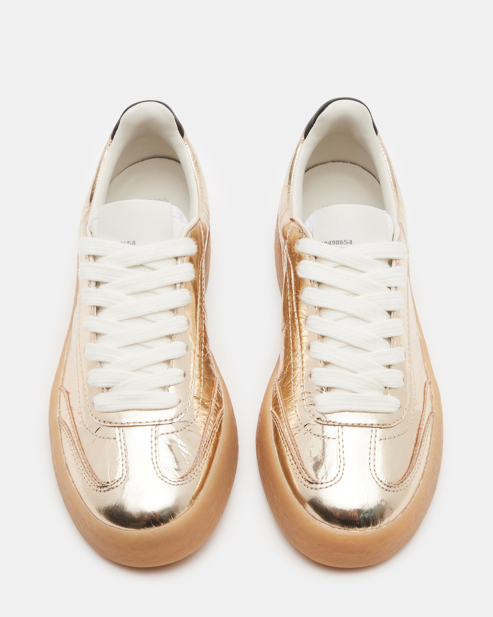 Close-up of lace-up design and patent leather texture on TUX Gold sneakers