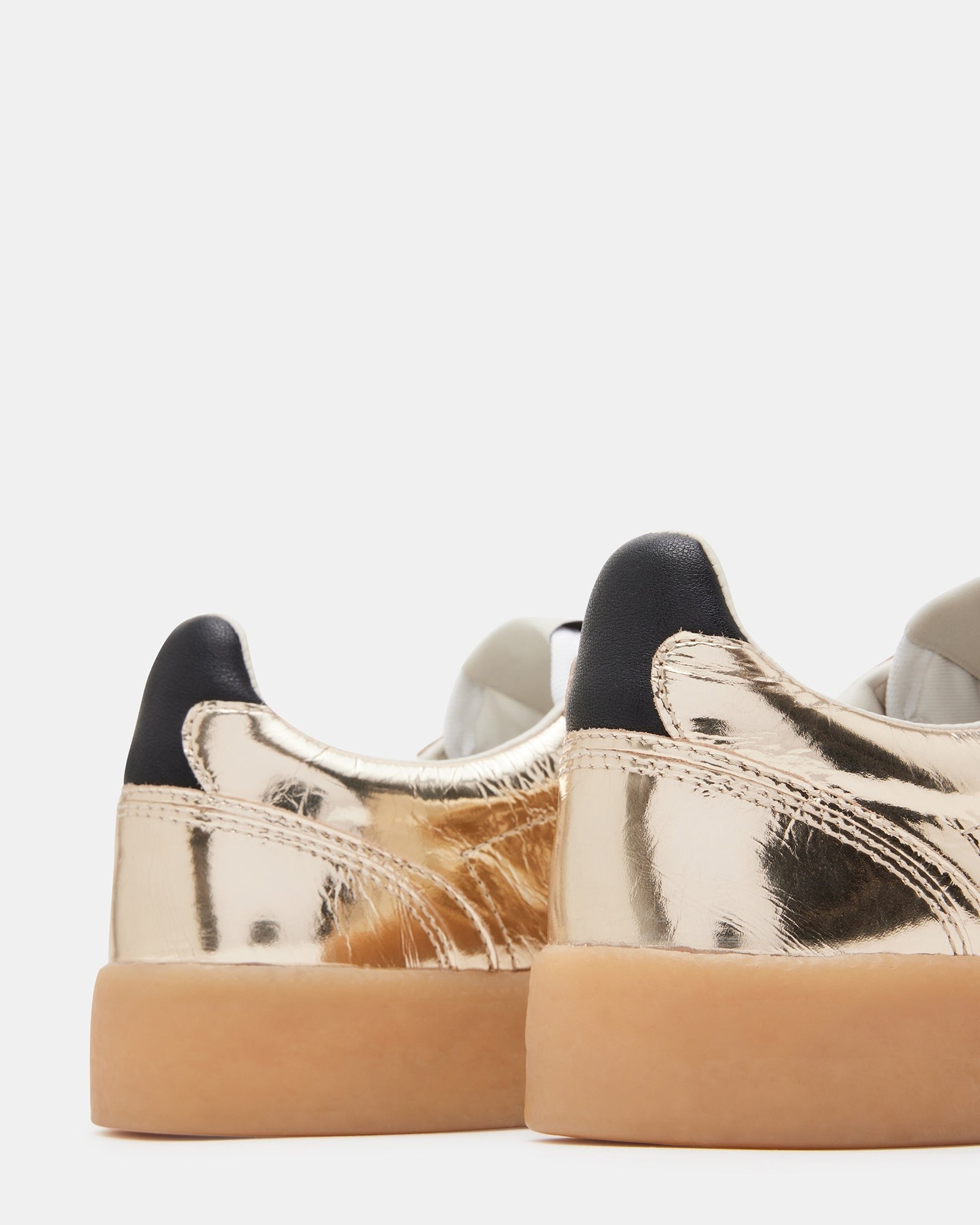 Side view of TUX Gold low-top sneakers showing sleek leather finish and gold details