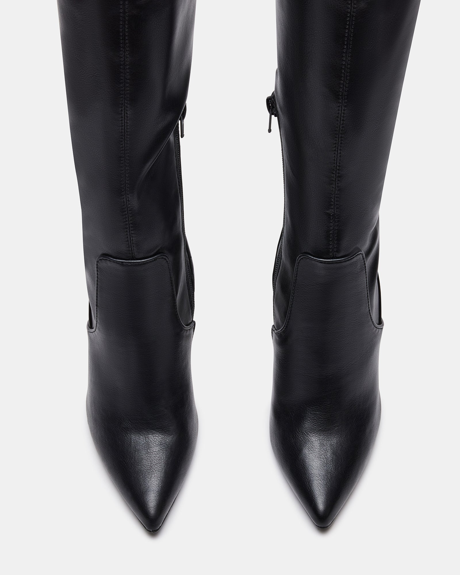 Close-up of vegan leather boots with reinforced top strap against a concrete backdrop.