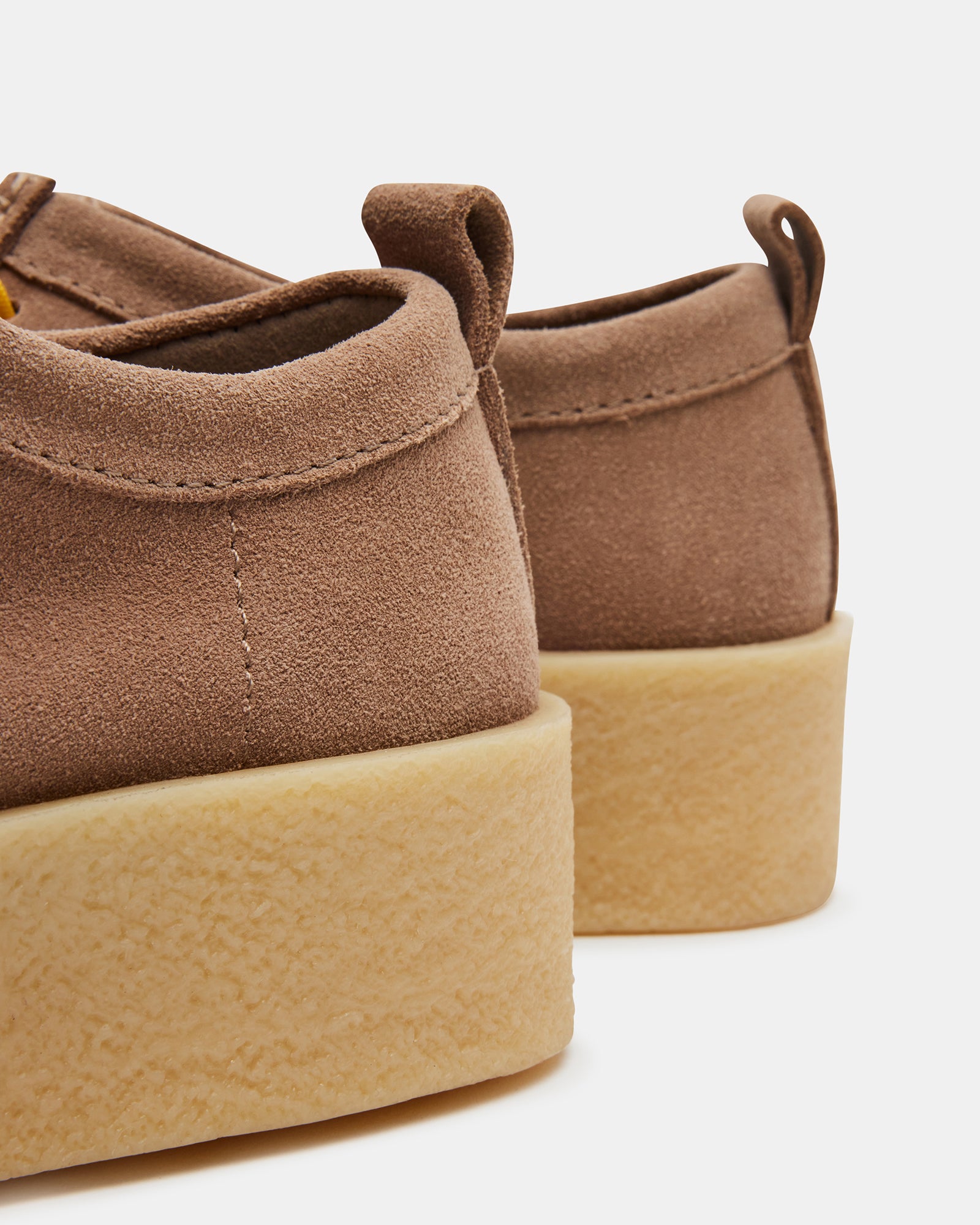 Close-up of taupe shoes with striped laces and textured suede surface